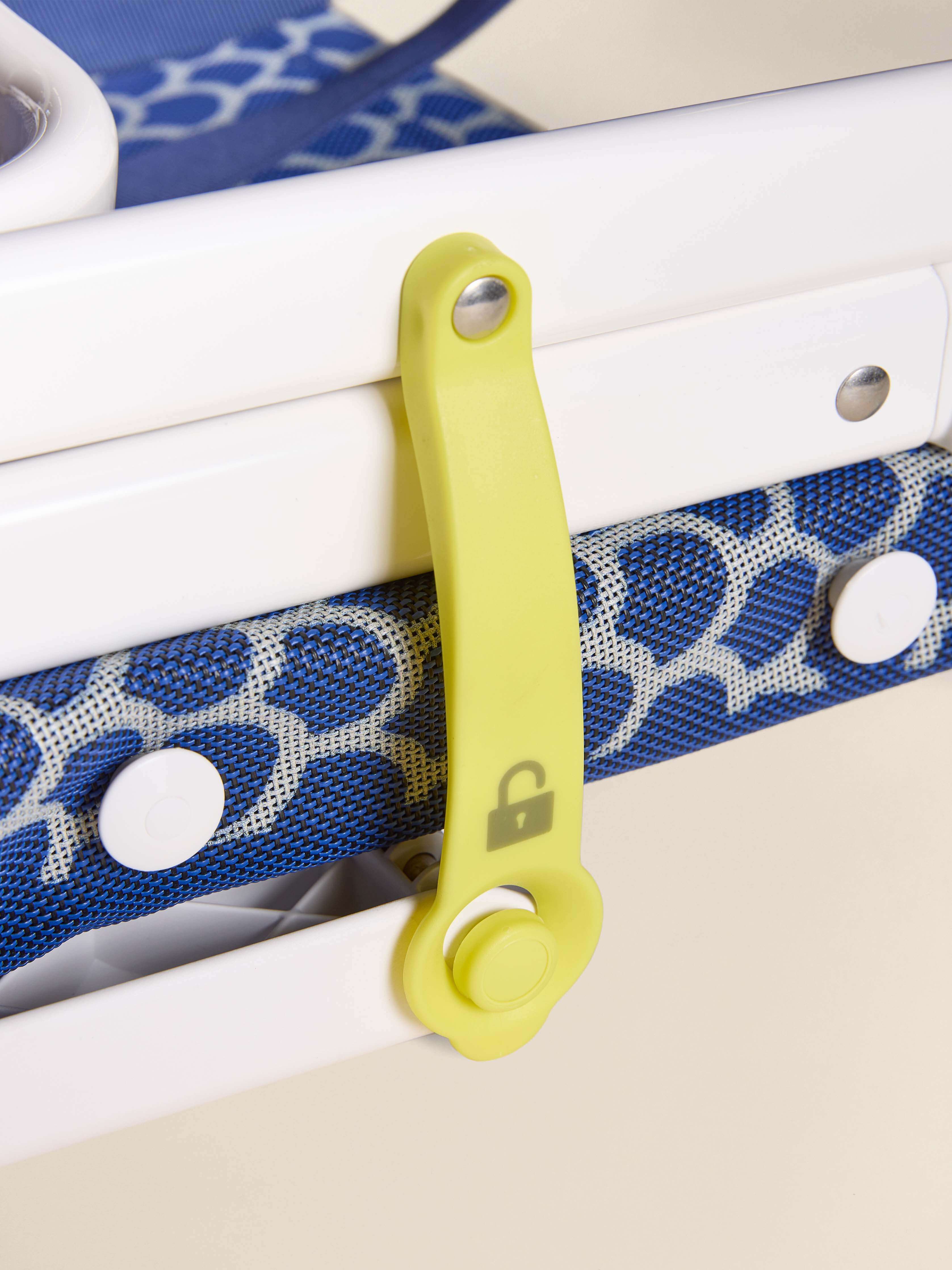 Blue folding chair with yellow lock strap detail against a beige background
