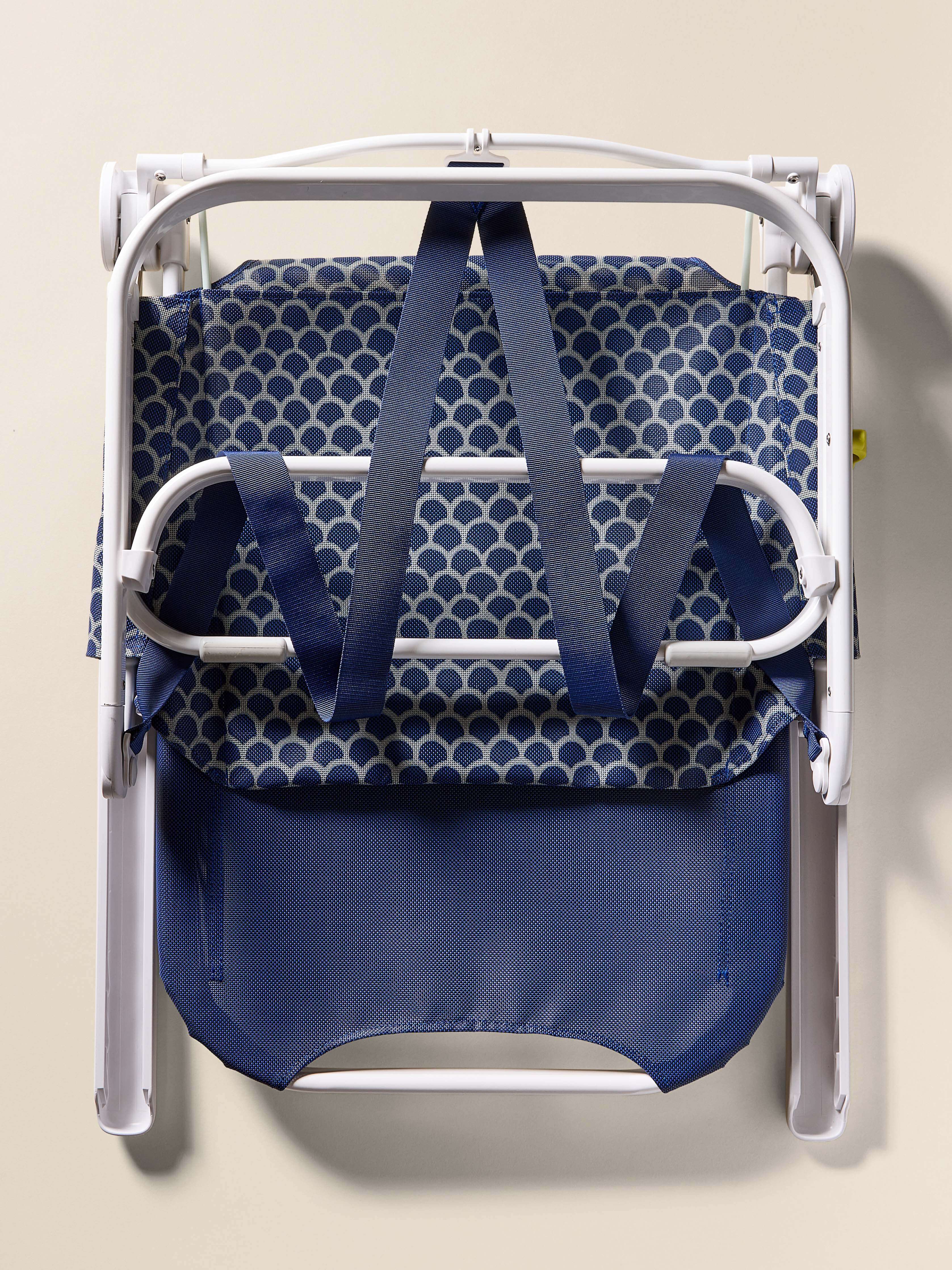 Blue folding chair with white frame on a beige background