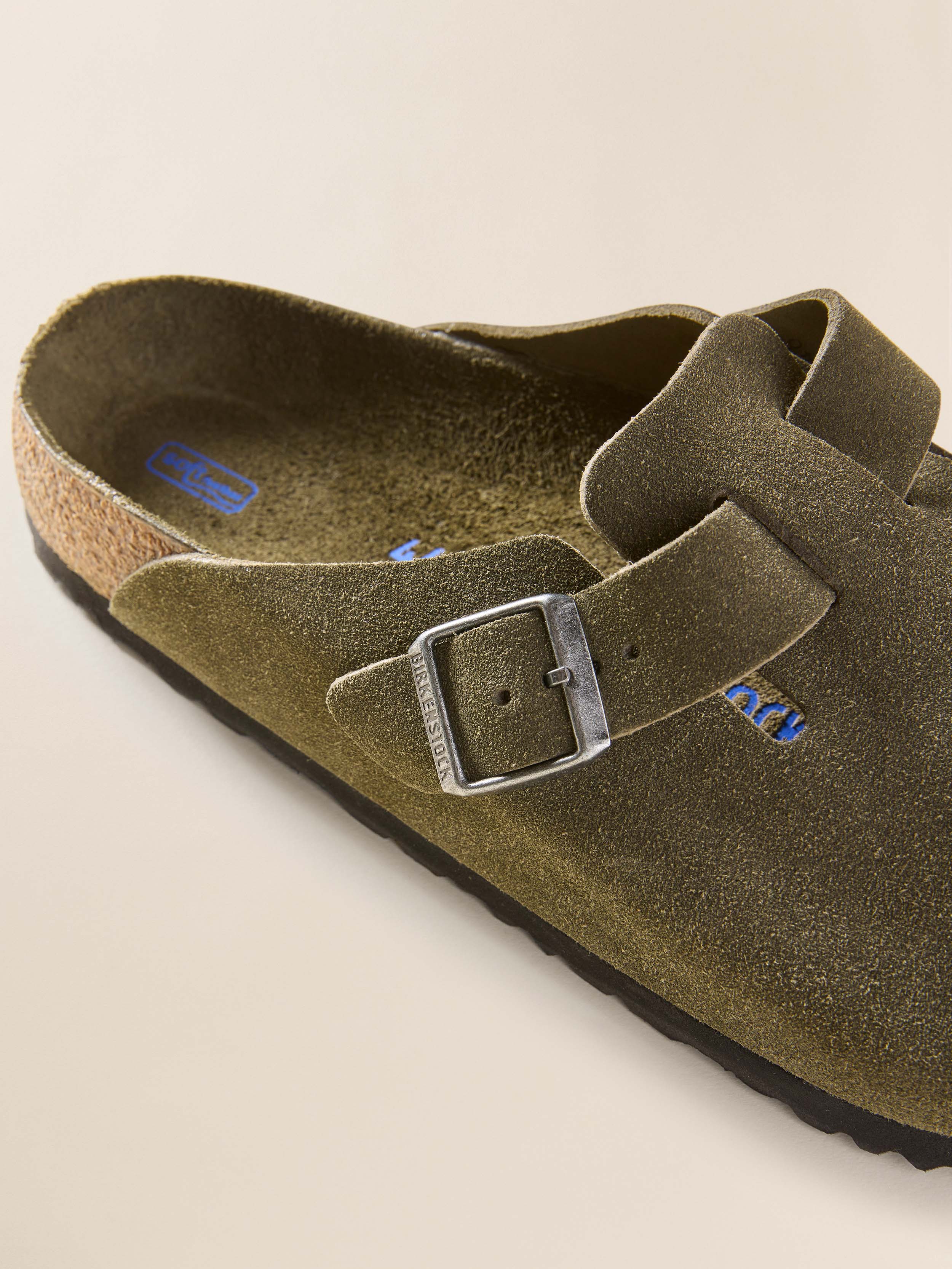 Green suede Birkenstock clog with buckles on a beige background