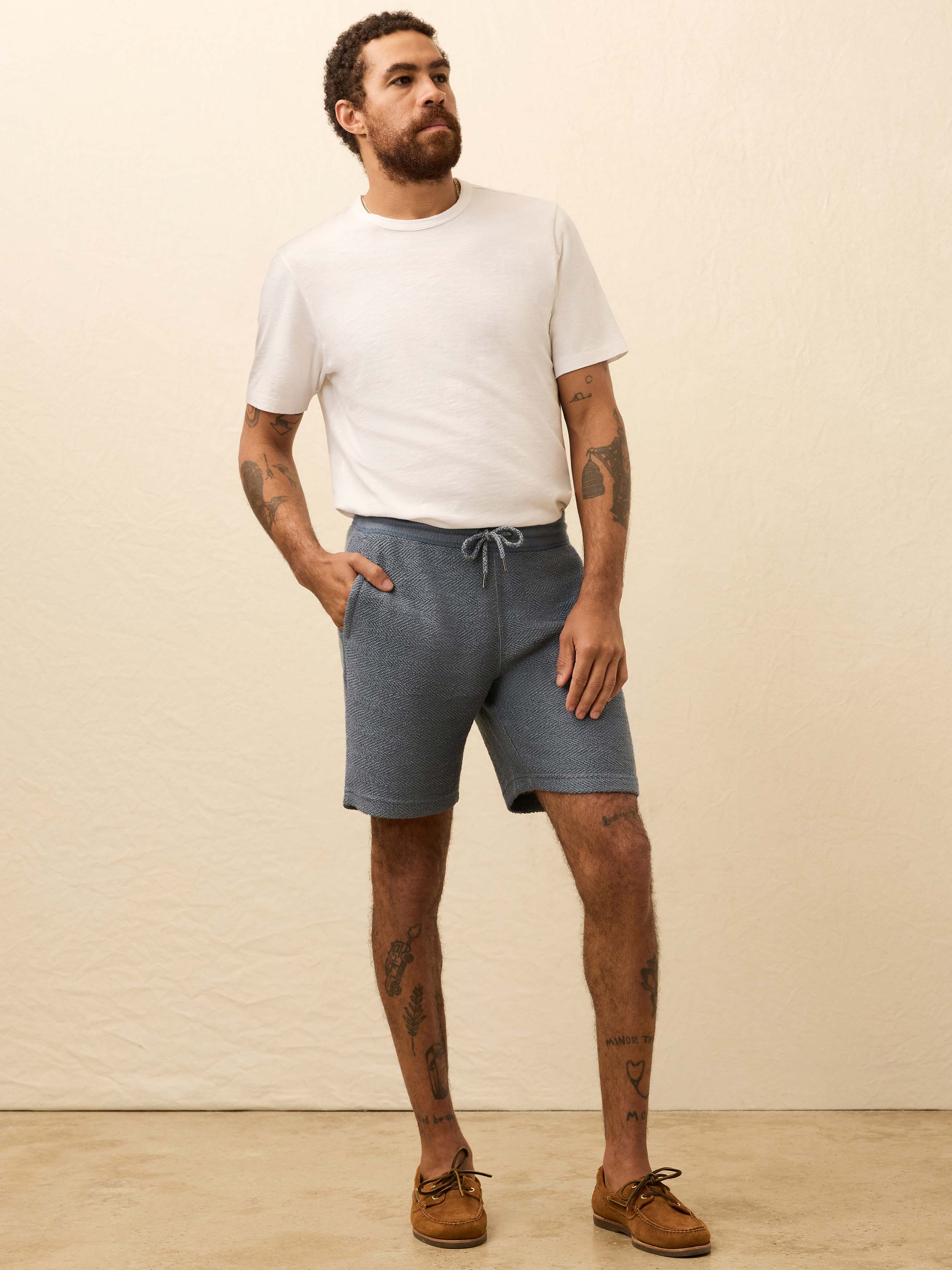 Man wearing blue shorts against a beige background