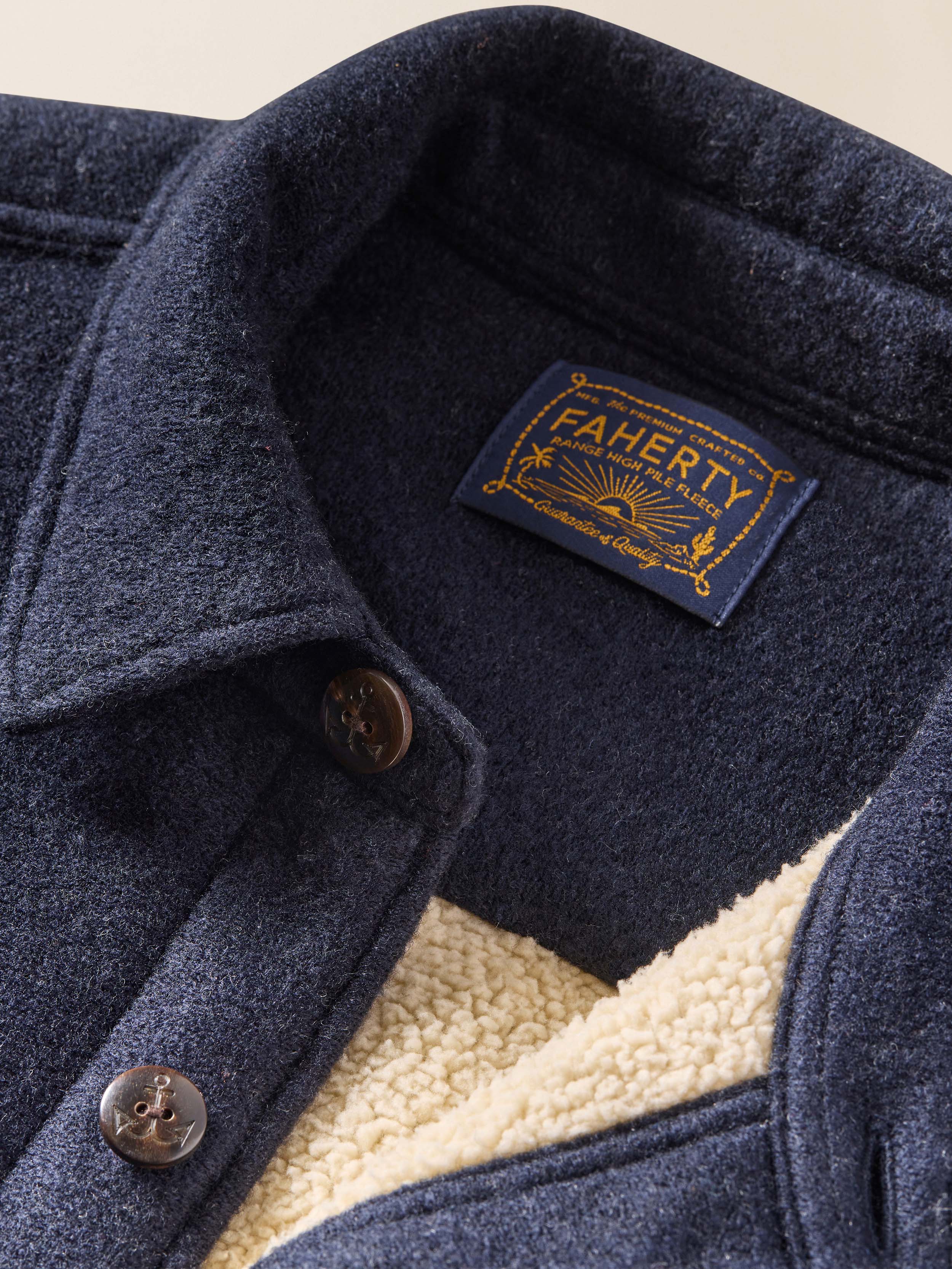 Close-up of a navy blue jacket with a Fajerty brand label on a beige background