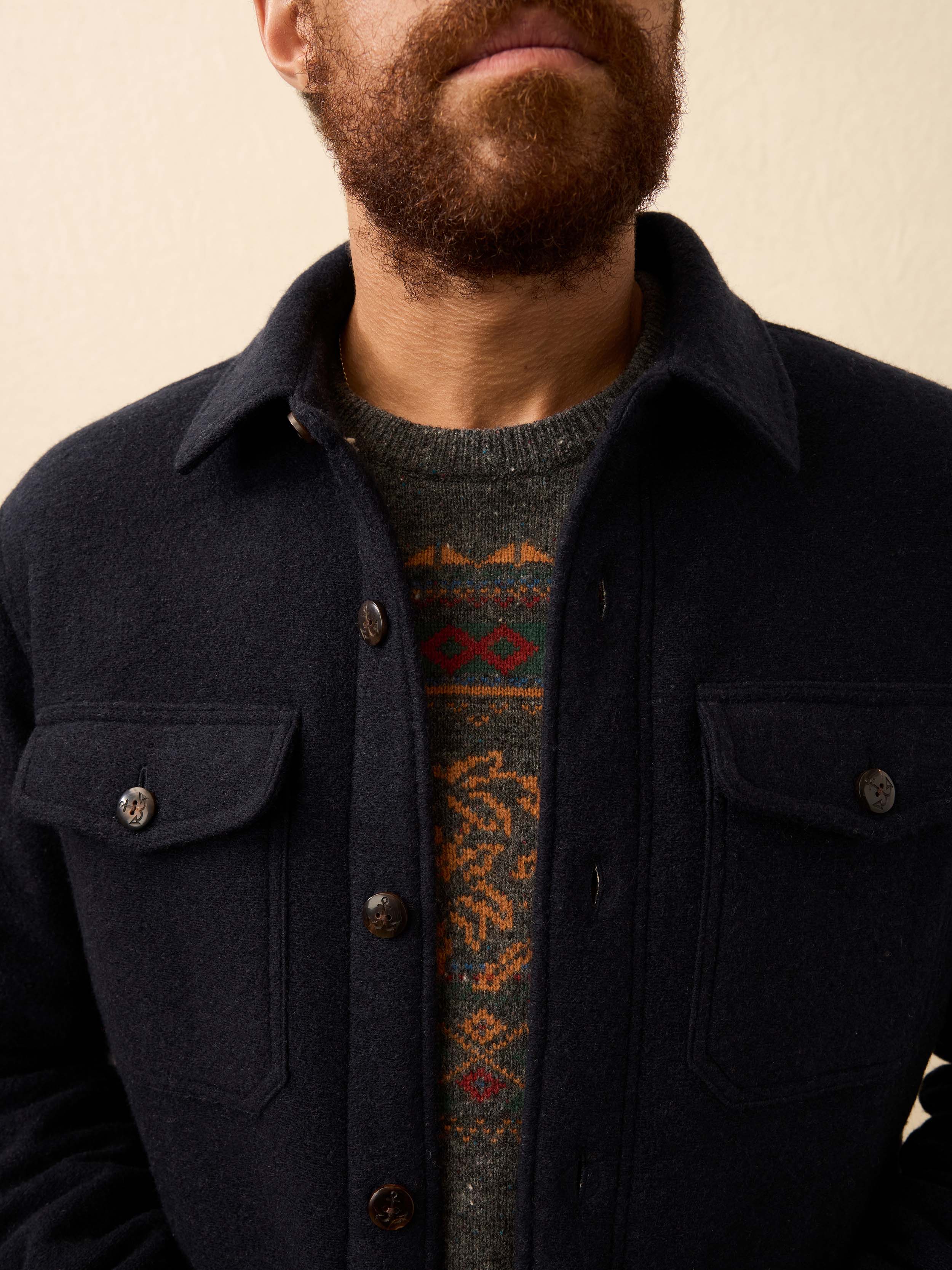Man wearing a dark navy shirt jacket against a beige background