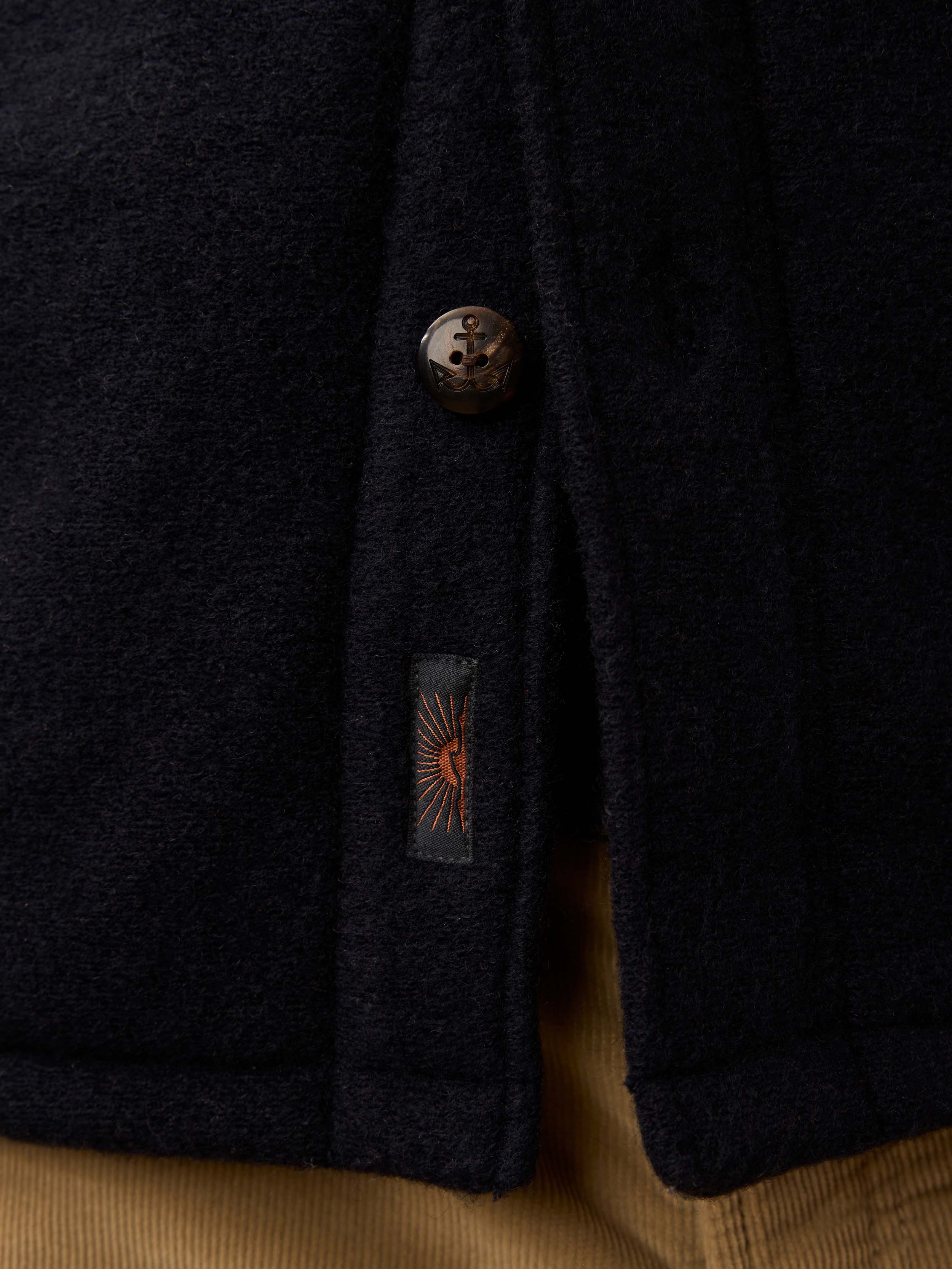 Close-up of a navy jacket with a button and Faherty brand label