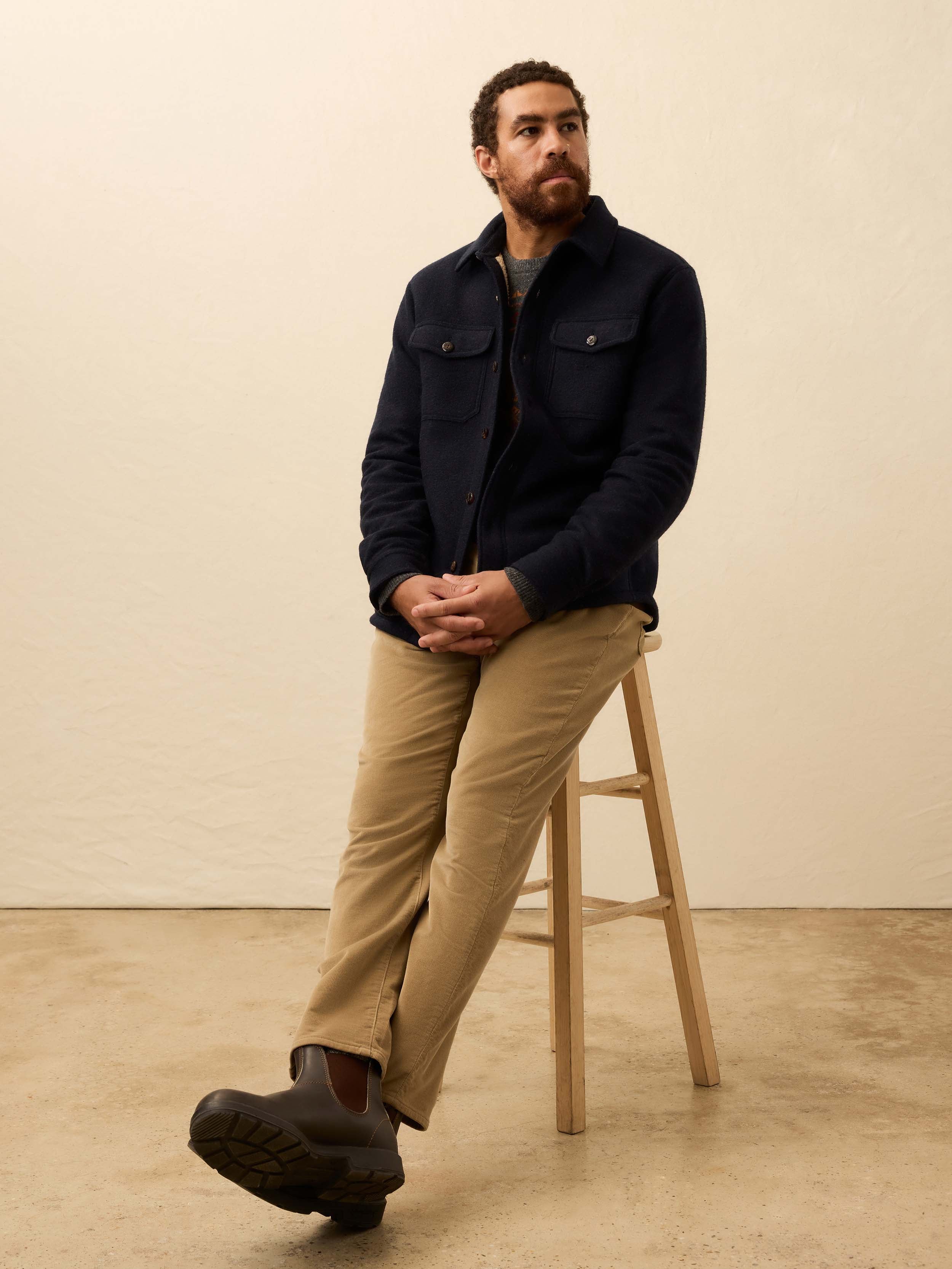 Man wearing a dark navy shirt jacket against a beige background