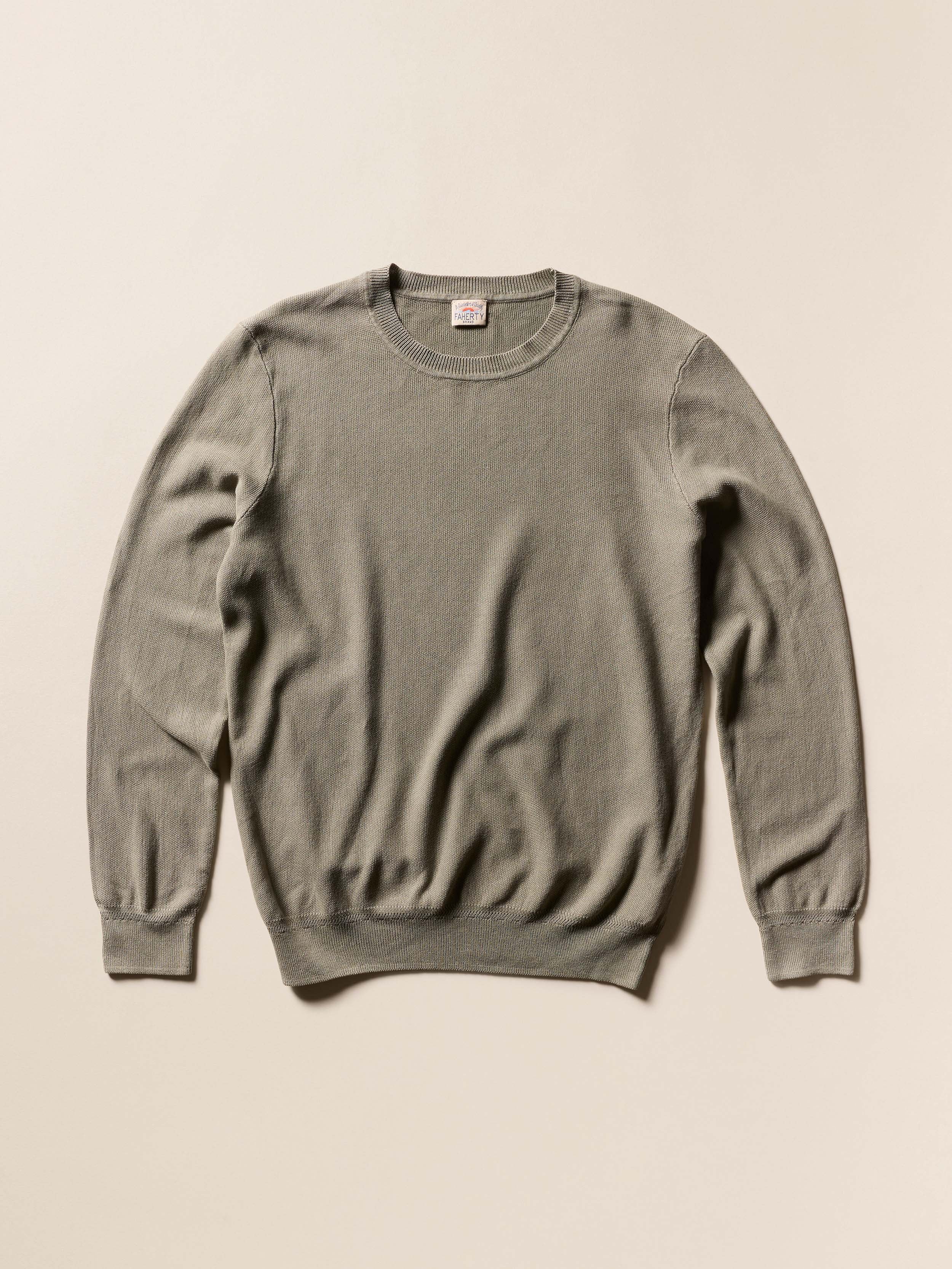 Sage green sweater on a beige background