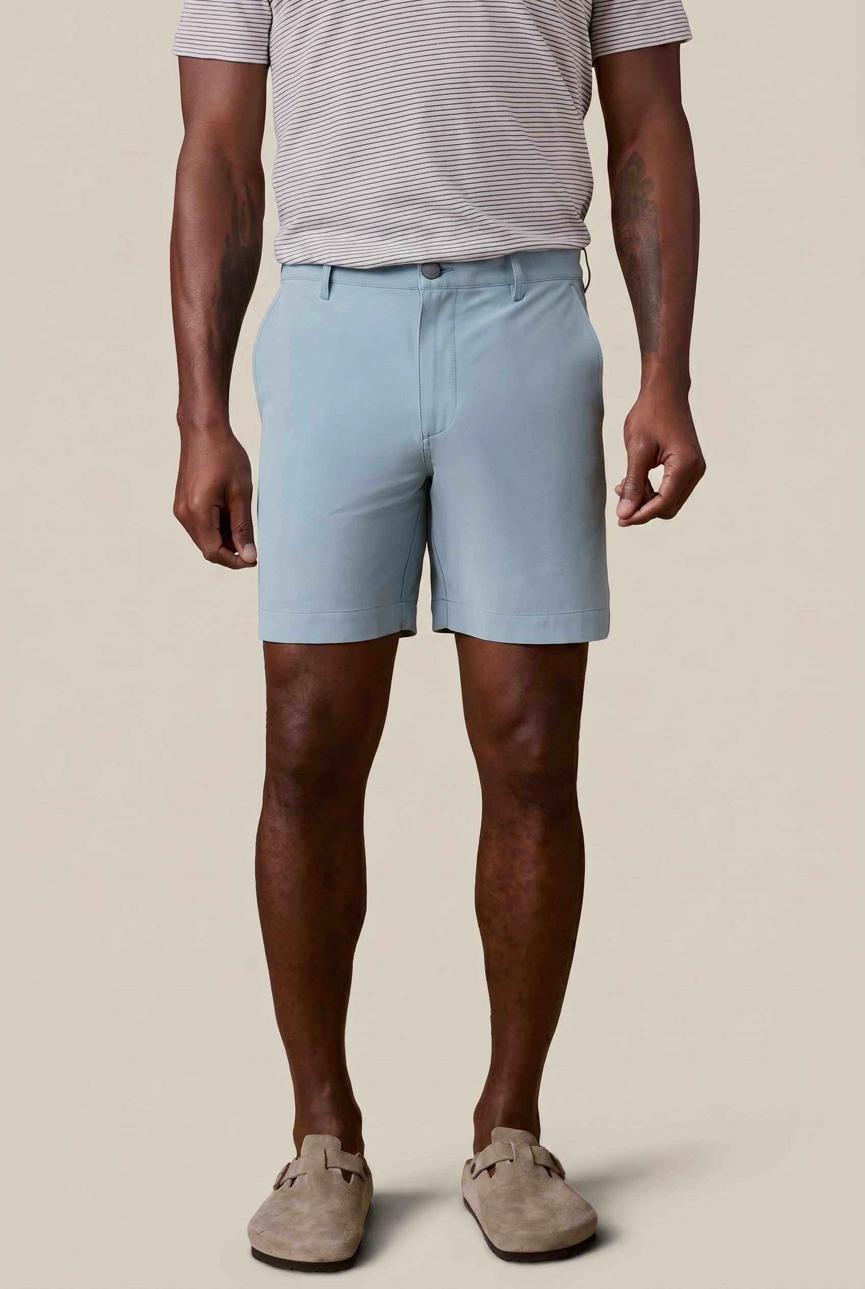 Man wearing light blue shorts and a striped shirt on a beige background