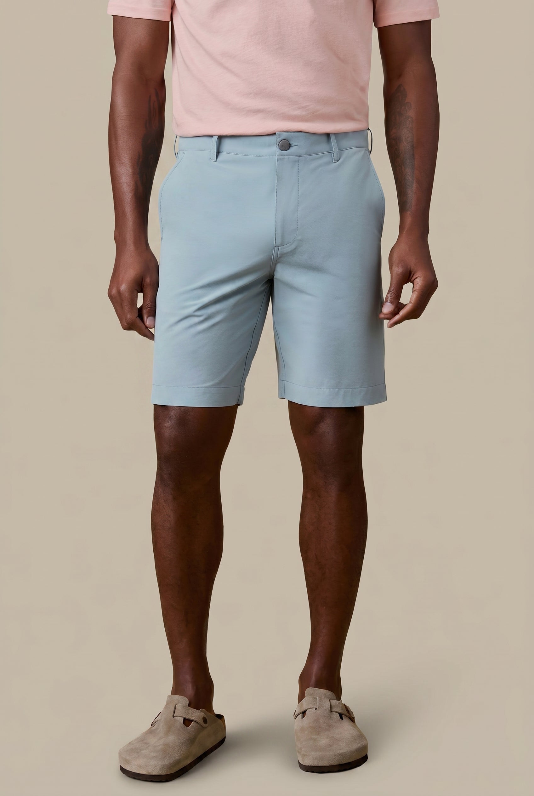 Man wearing light blue shorts and a pink shirt on a beige background