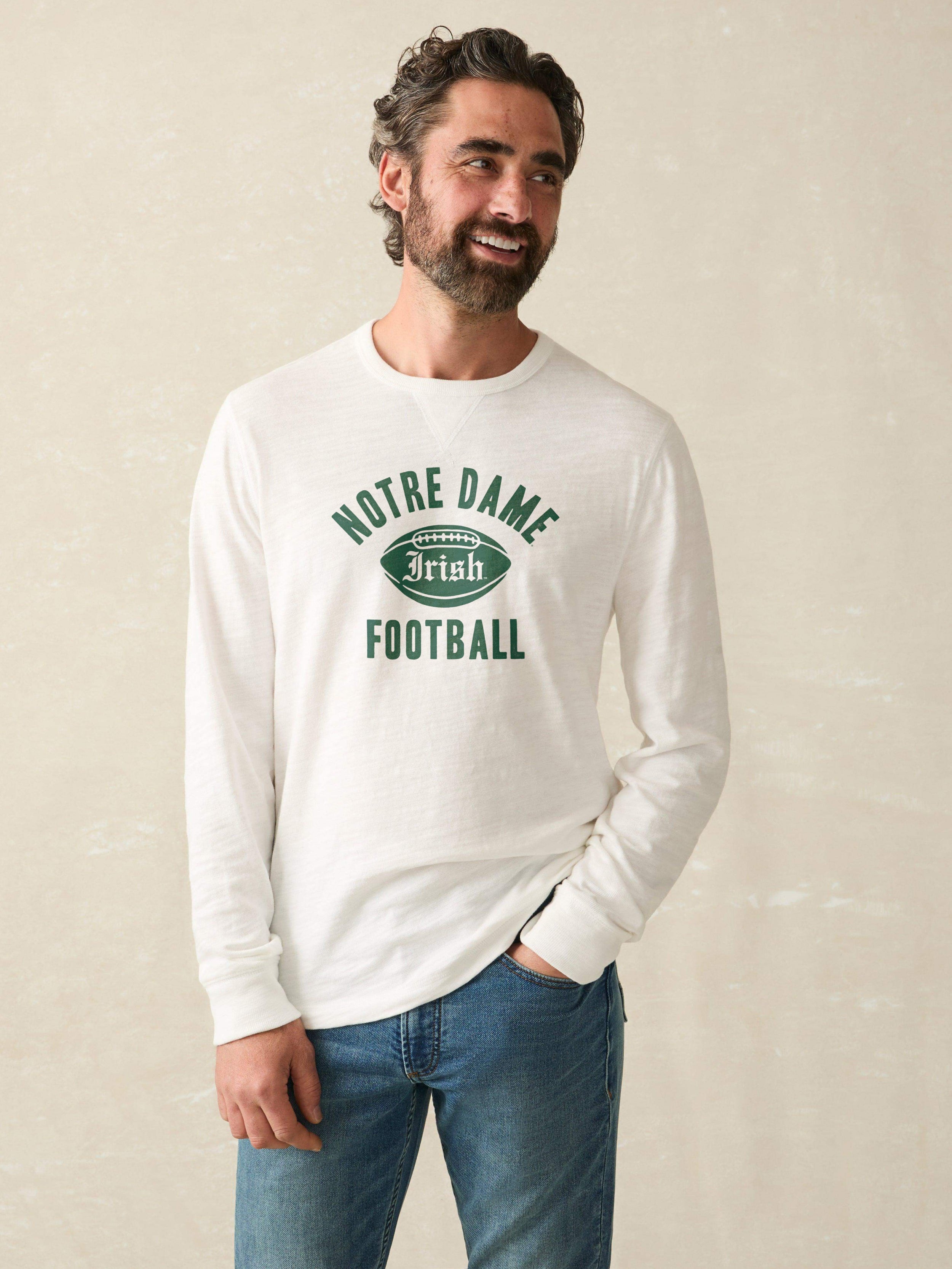 Man wearing a white long-sleeve shirt with 'Notre Dame Football' graphic on a beige background