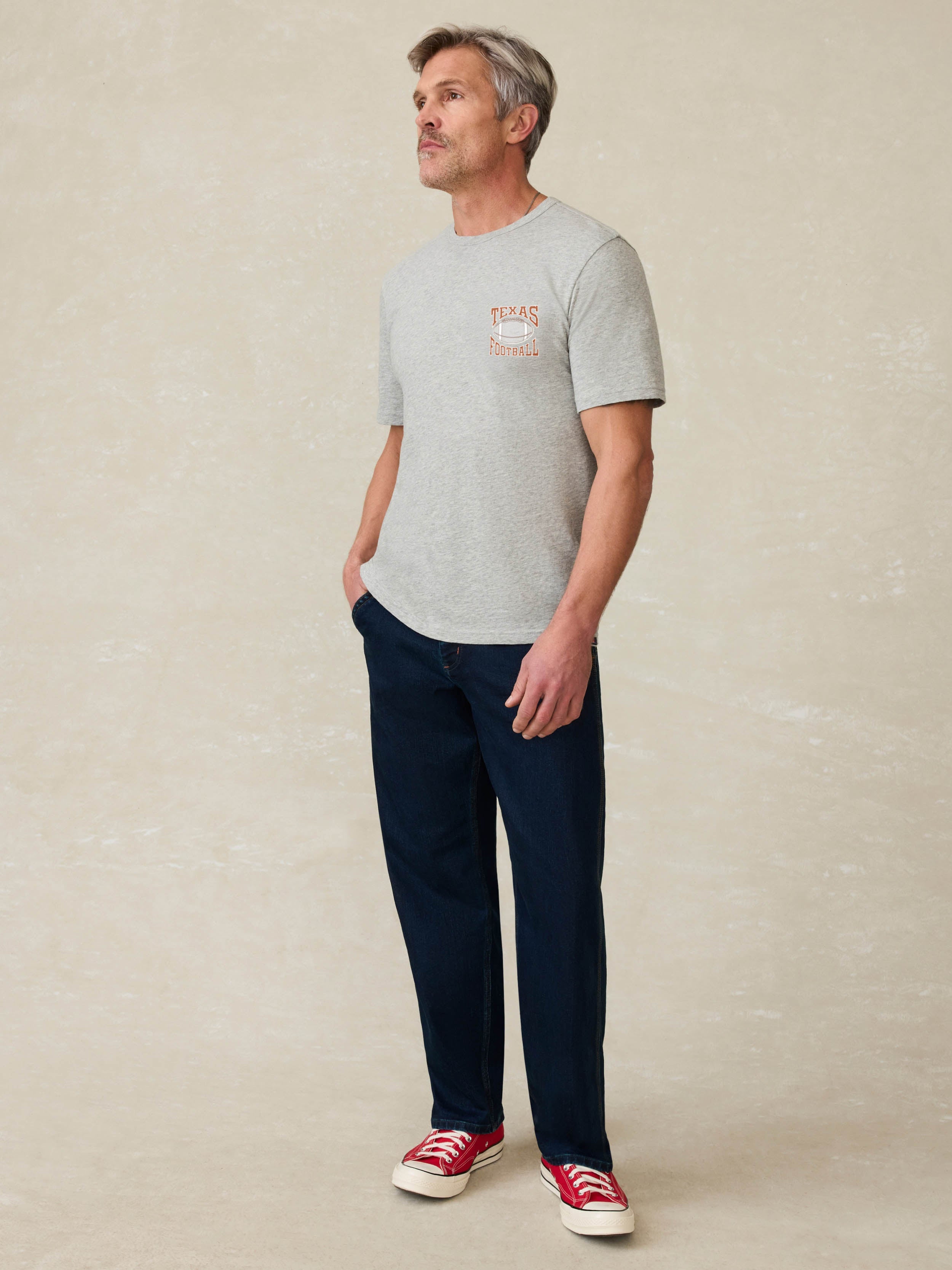Grey short sleeve t-shirt with UT Austin graphic on the left chest against a beige background