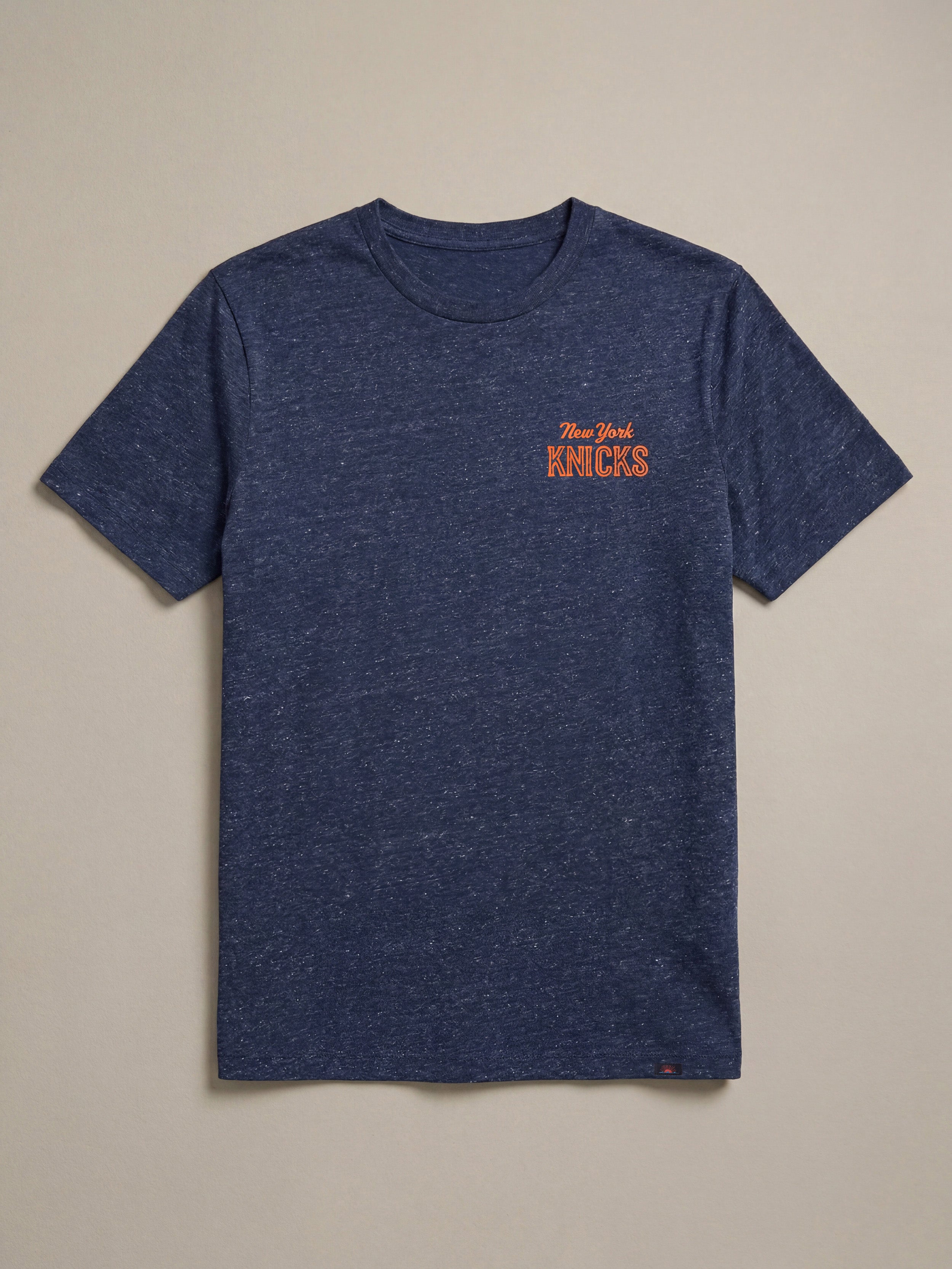 Blue t-shirt with 'New York Knicks' logo on a beige background