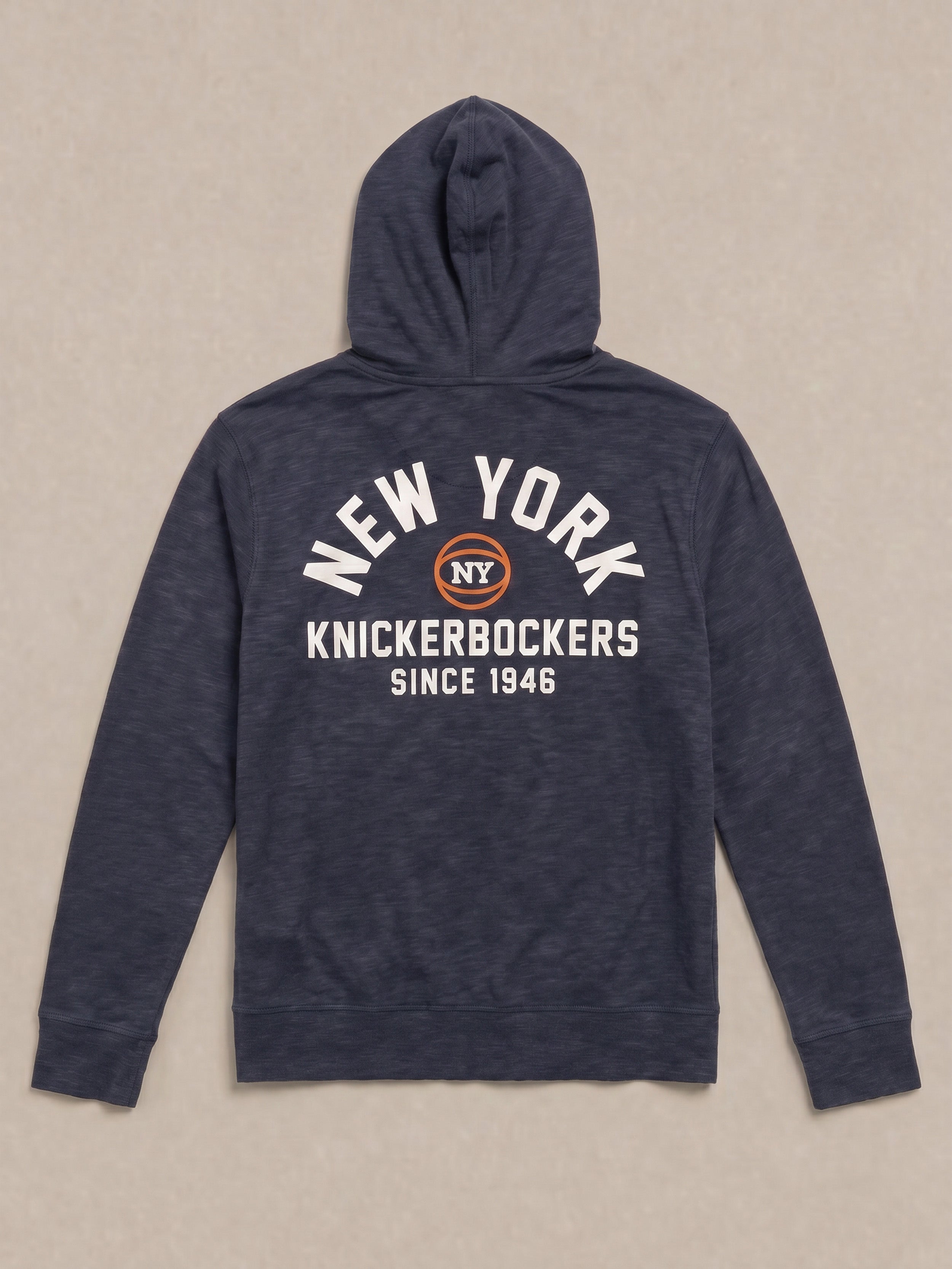 Navy blue hoodie with 'New York Knickerbockers' graphic text on the back against a beige background