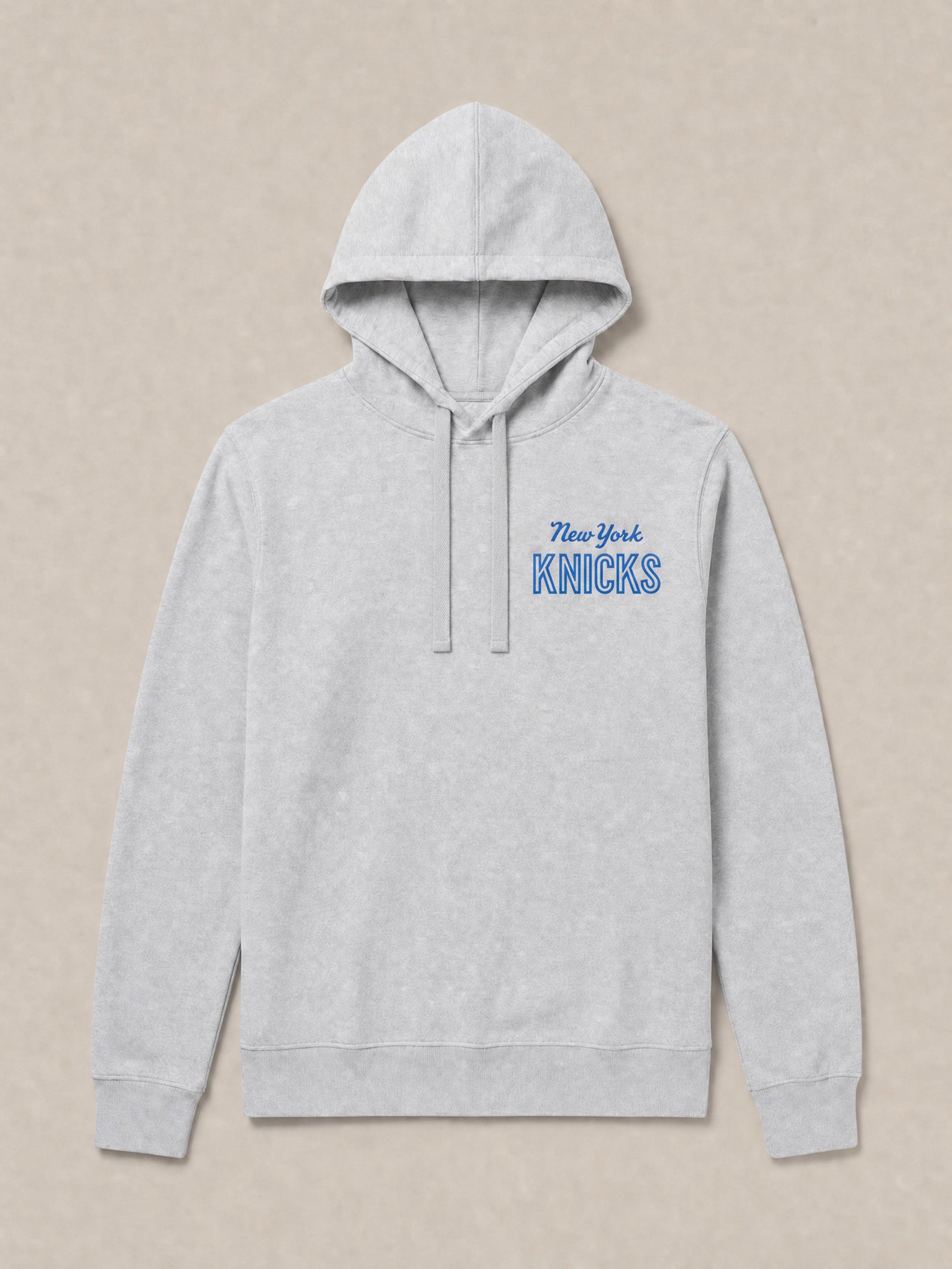 Gray hoodie with 'New York Knicks' graphic text on the left chest against a beige background