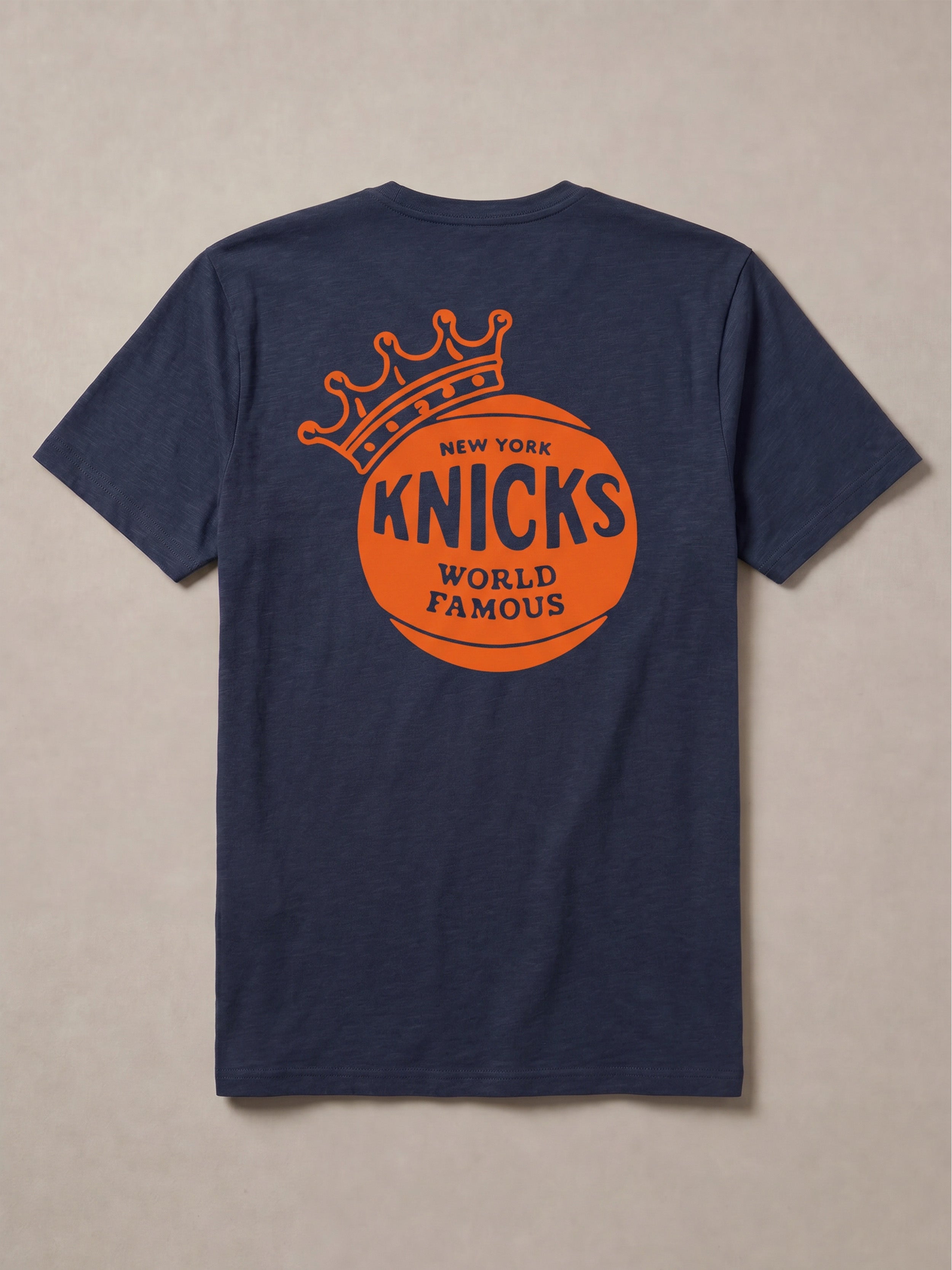 Navy blue t-shirt with orange 'New York Knicks World Famous' graphic on the back against a beige background