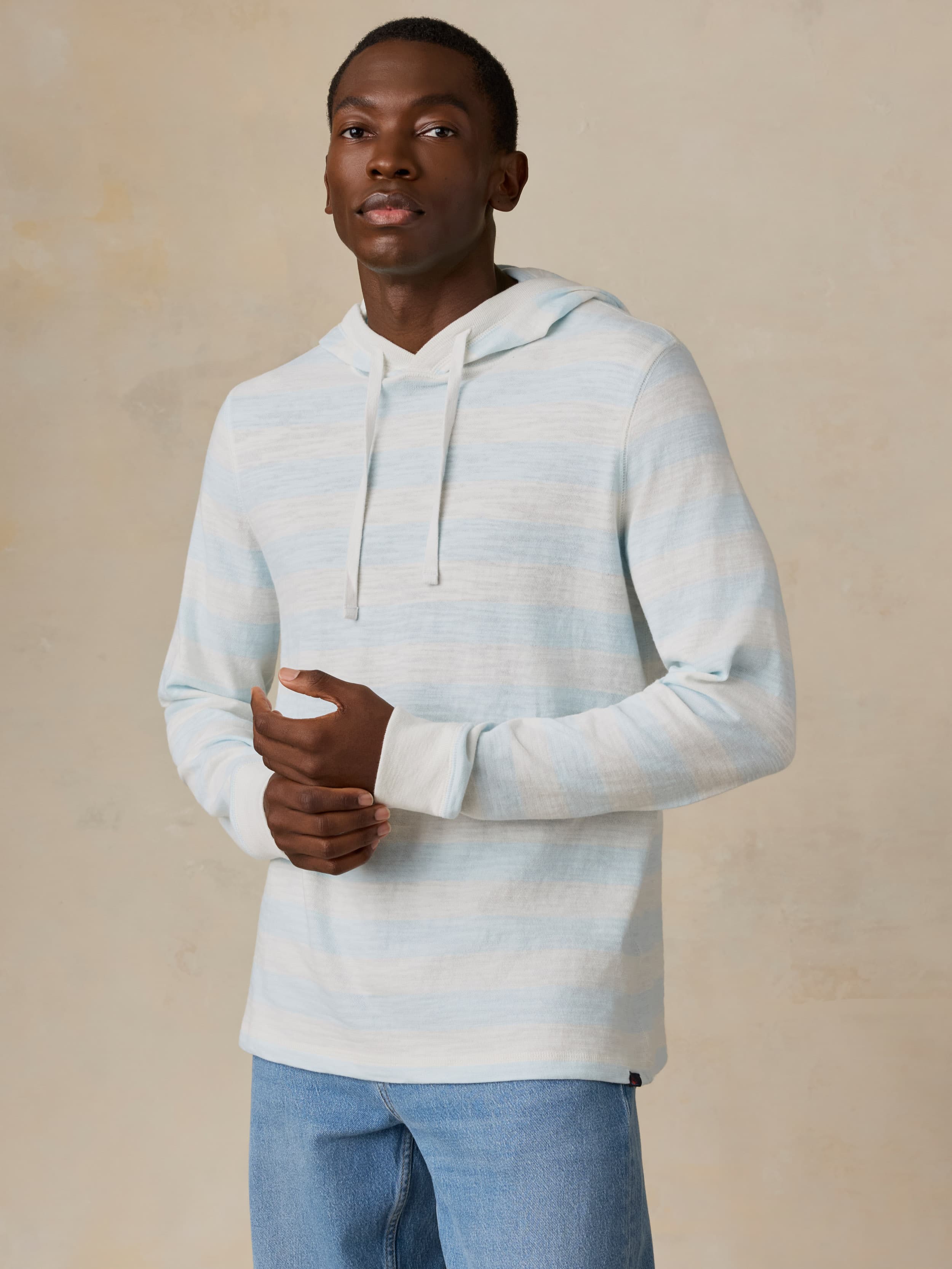 Man wearing a light blue and white striped hoodie against a beige background