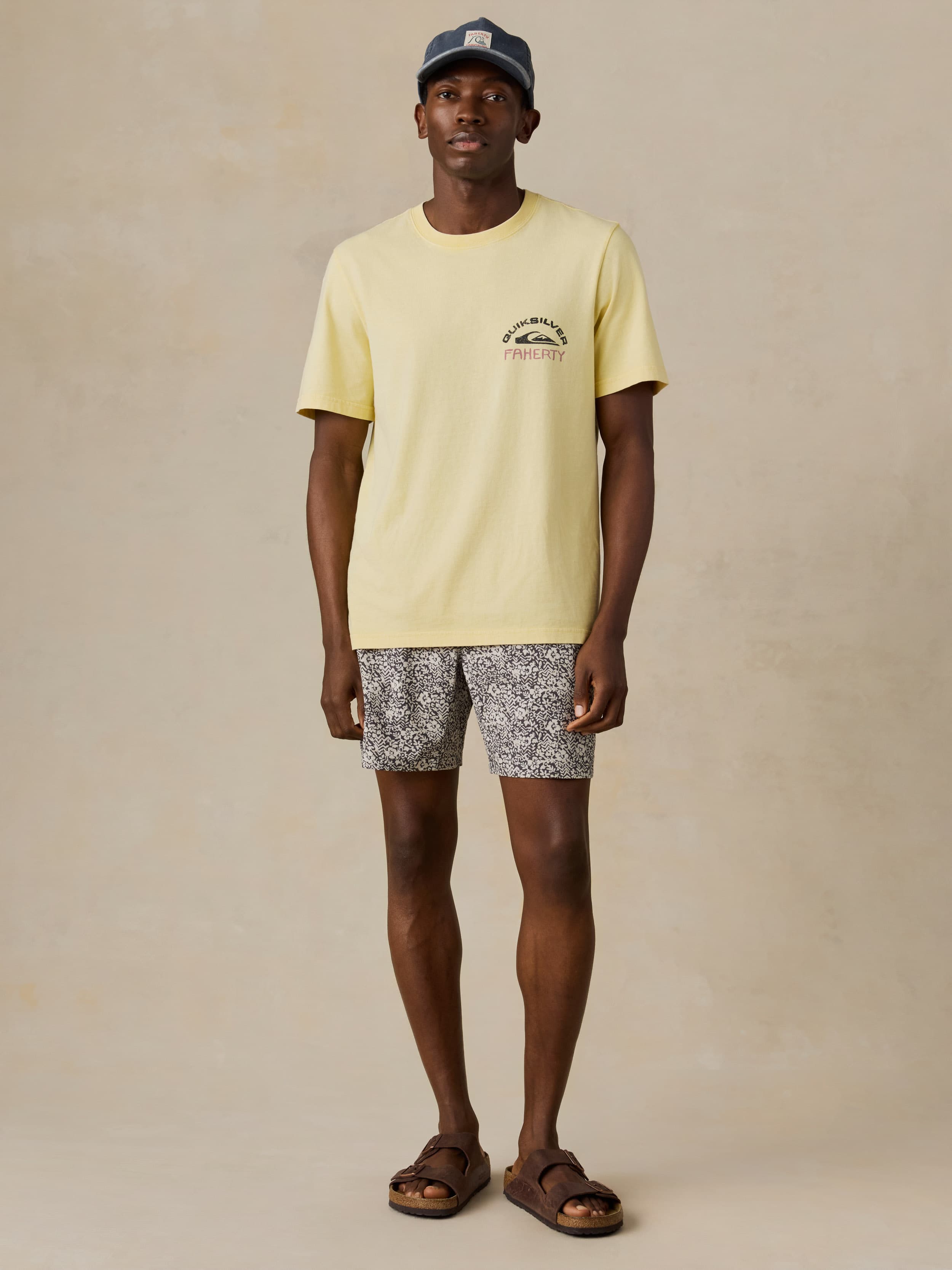Man wearing a light yellow t-shirt and black and white patterned shorts on a beige background