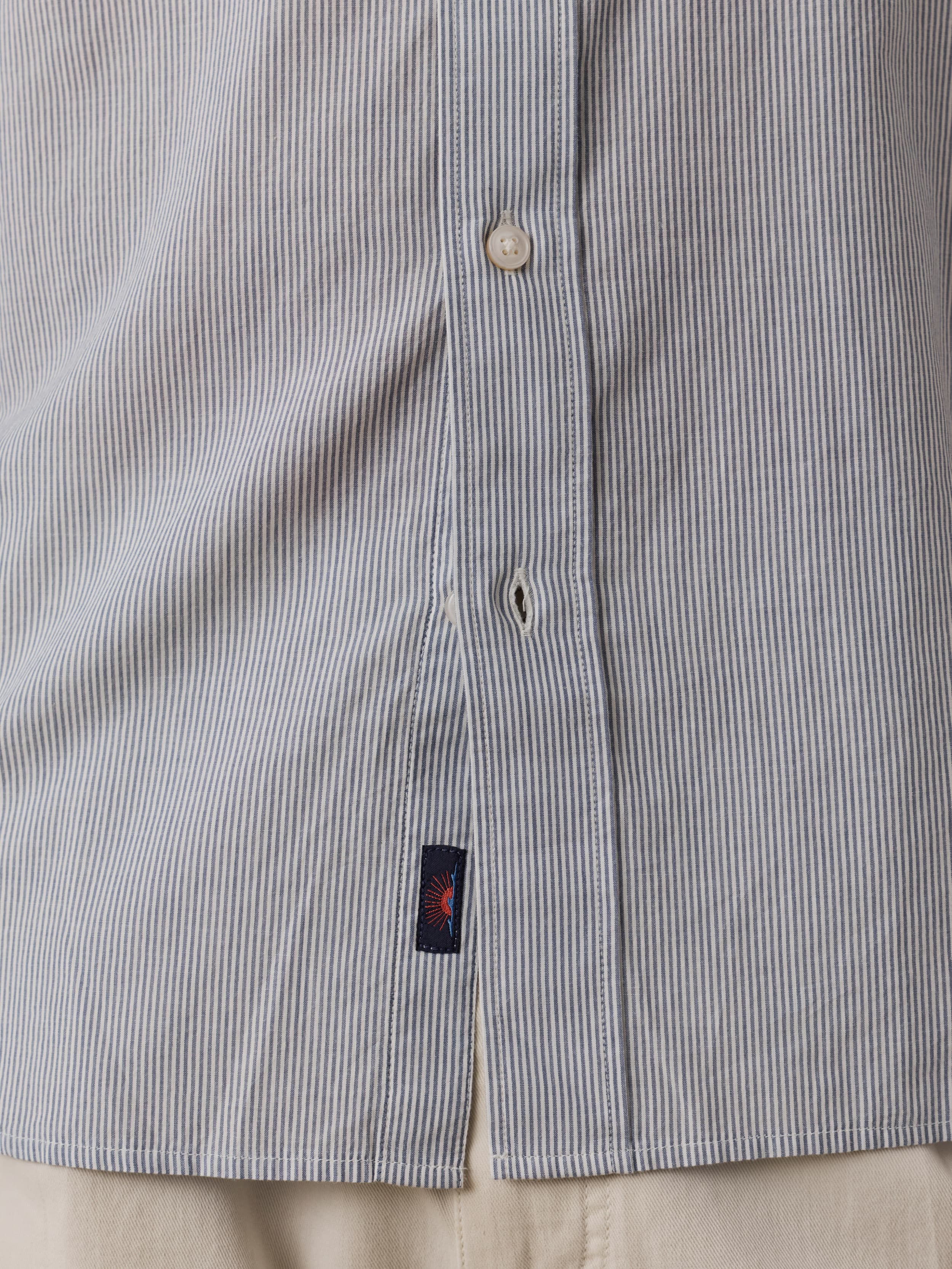 Close-up of a striped shirt with a Faherty brand label near the hem