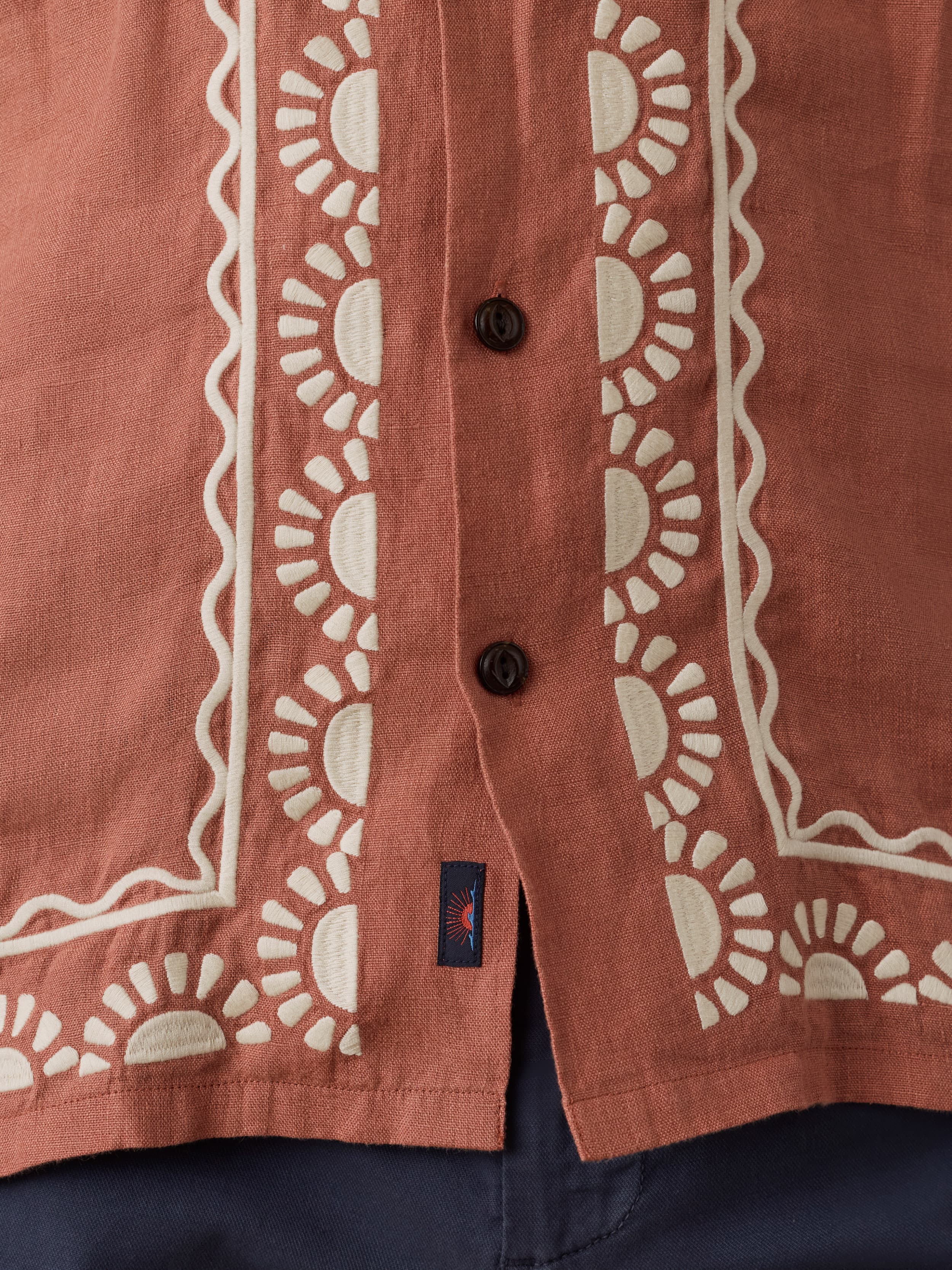 Close-up of a red embroidered shirt with white geometric patterns and a Faherty brand logo.
