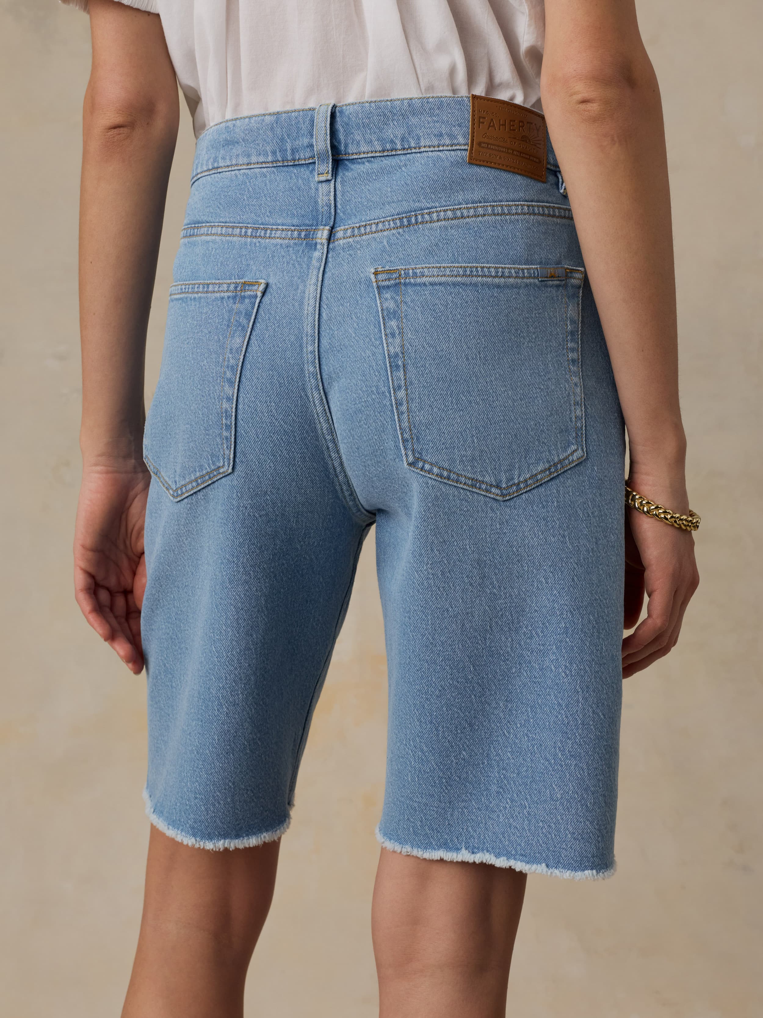 Woman wearing light blue denim shorts on a beige background