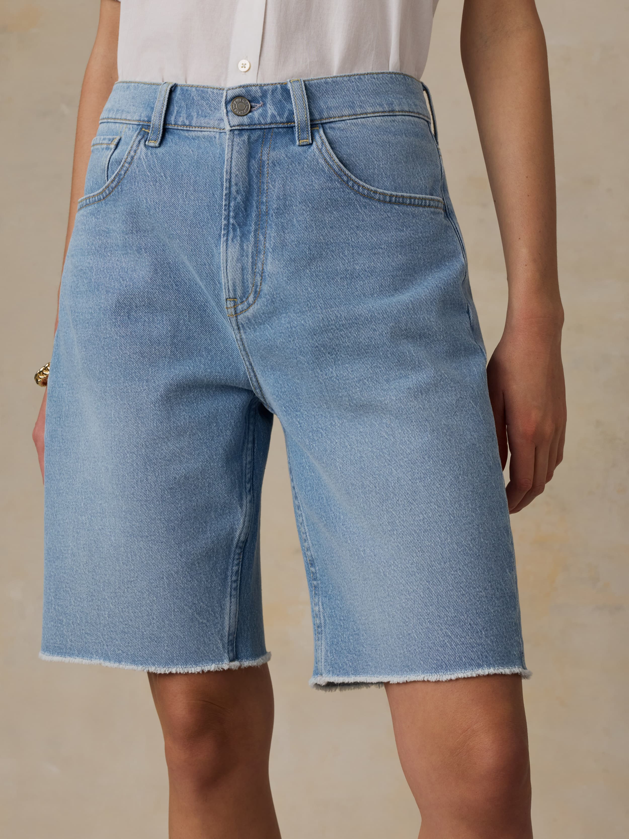 Woman wearing light blue denim shorts on a beige background