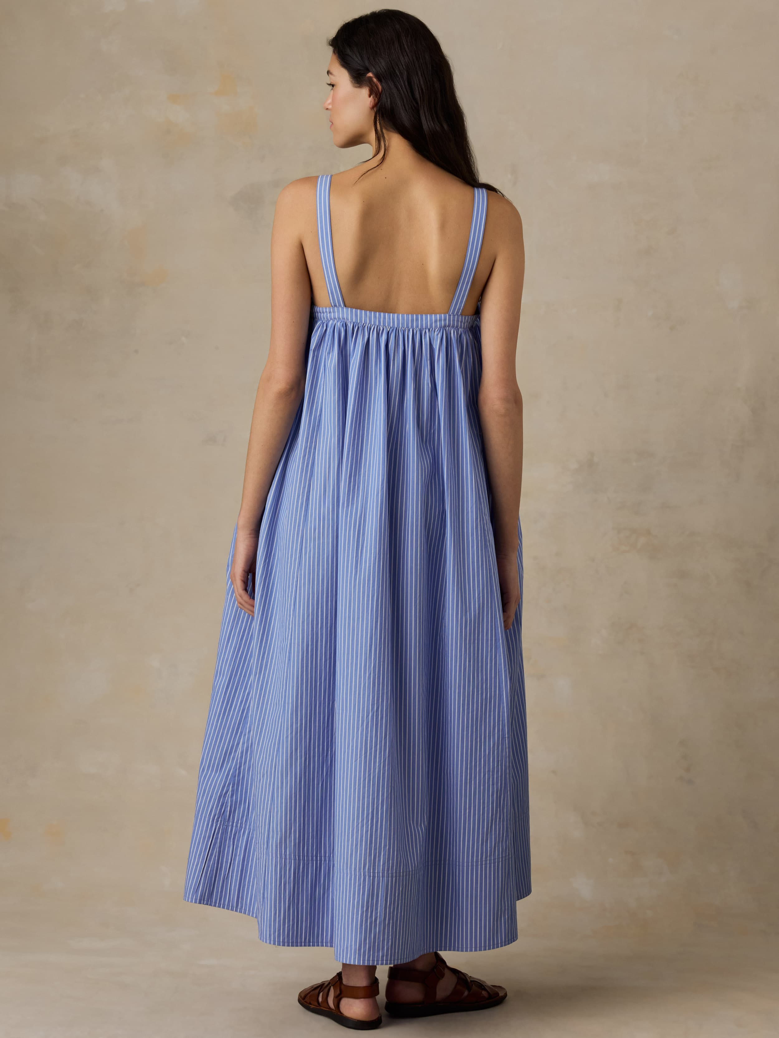 Woman wearing a blue striped dress against a beige background