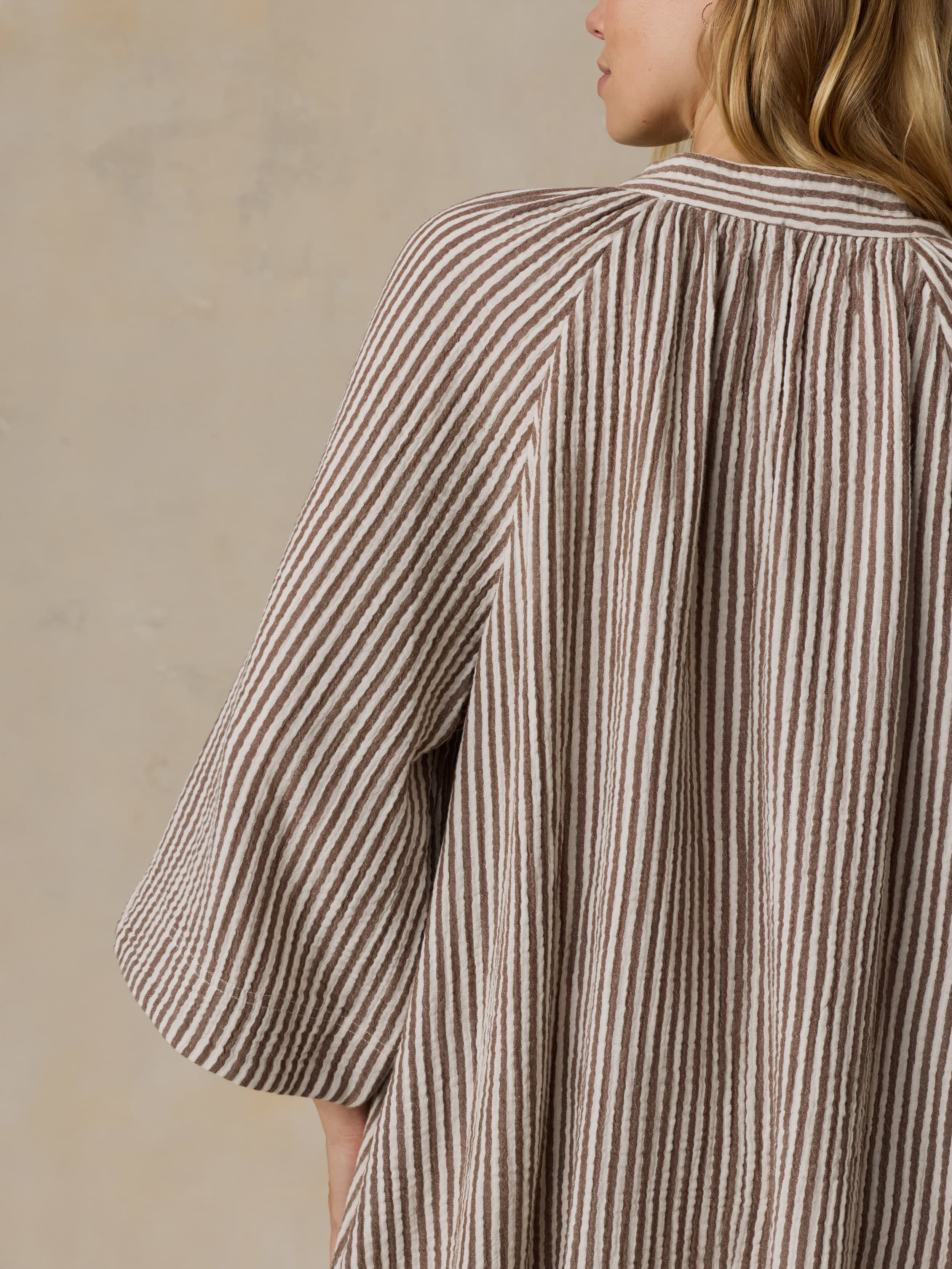 Woman wearing a brown striped dress against a neutral background