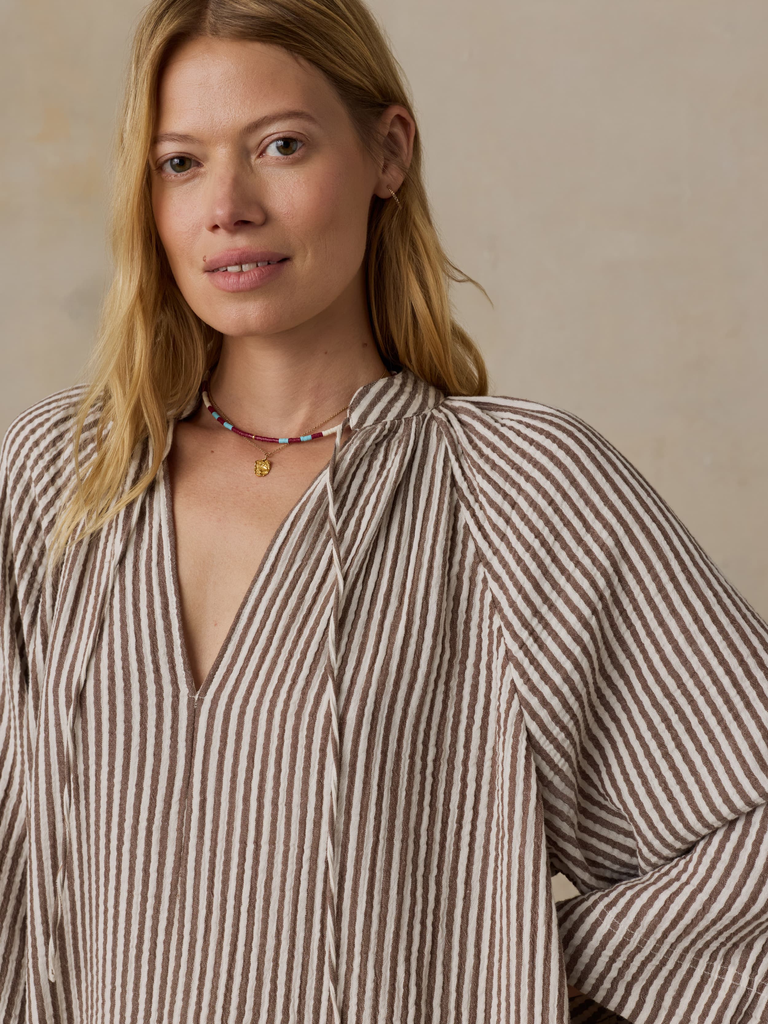 Woman wearing a brown striped dress against a neutral background