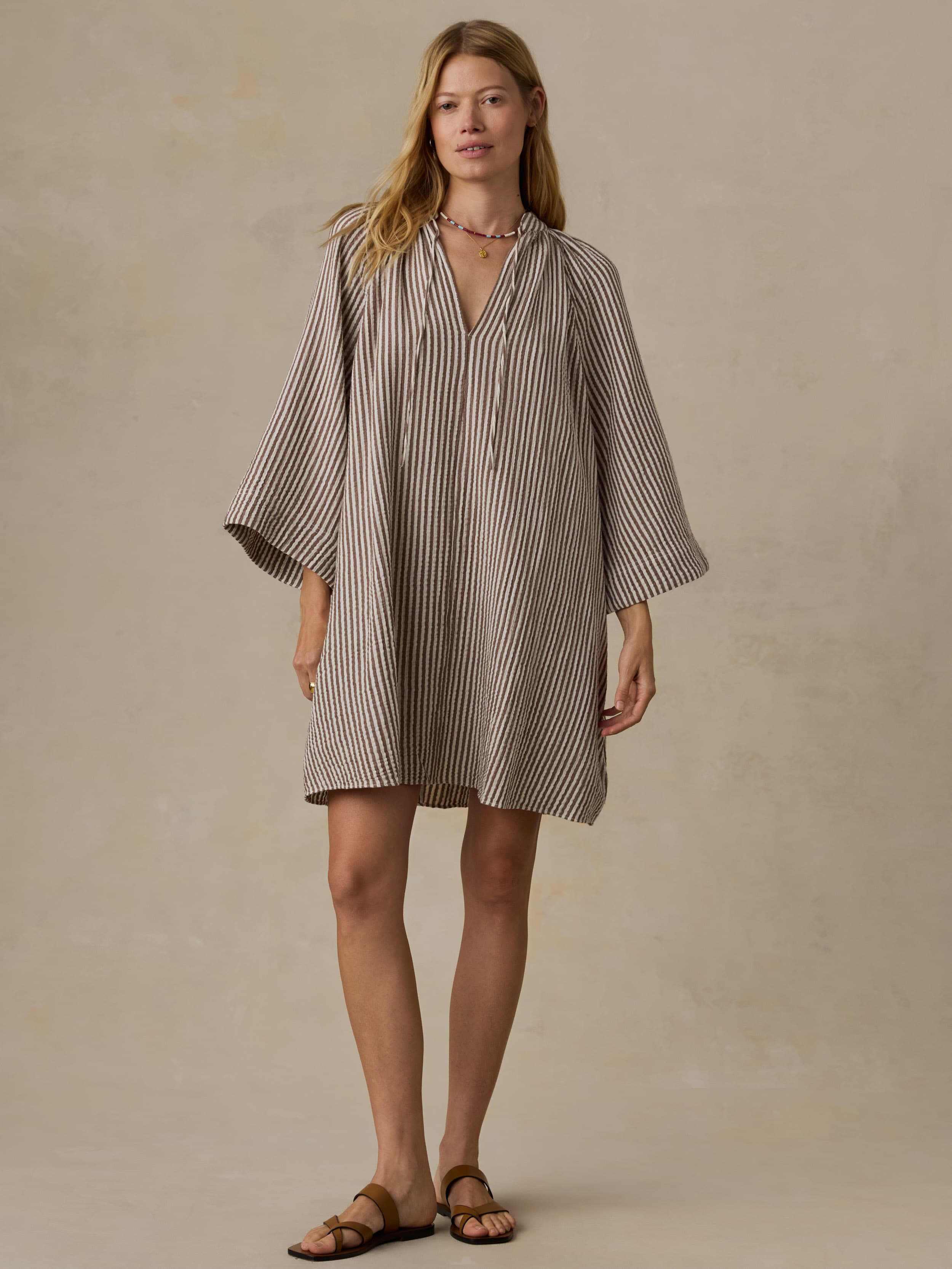 Woman wearing a brown striped dress against a neutral background