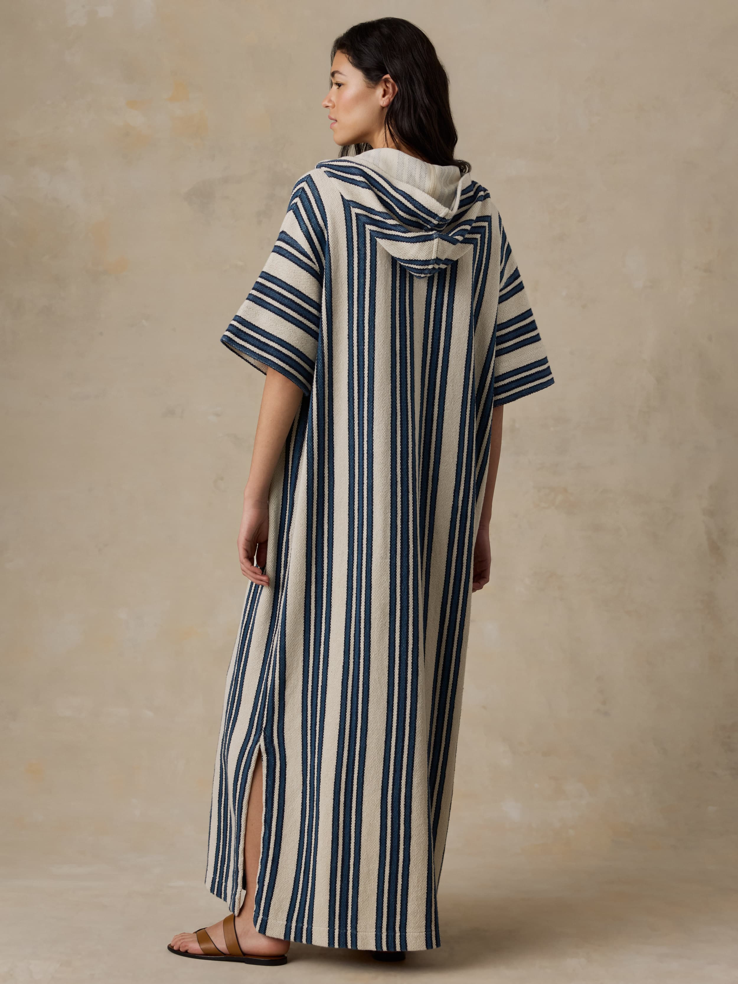 Woman wearing a striped dress with a hood against a beige background
