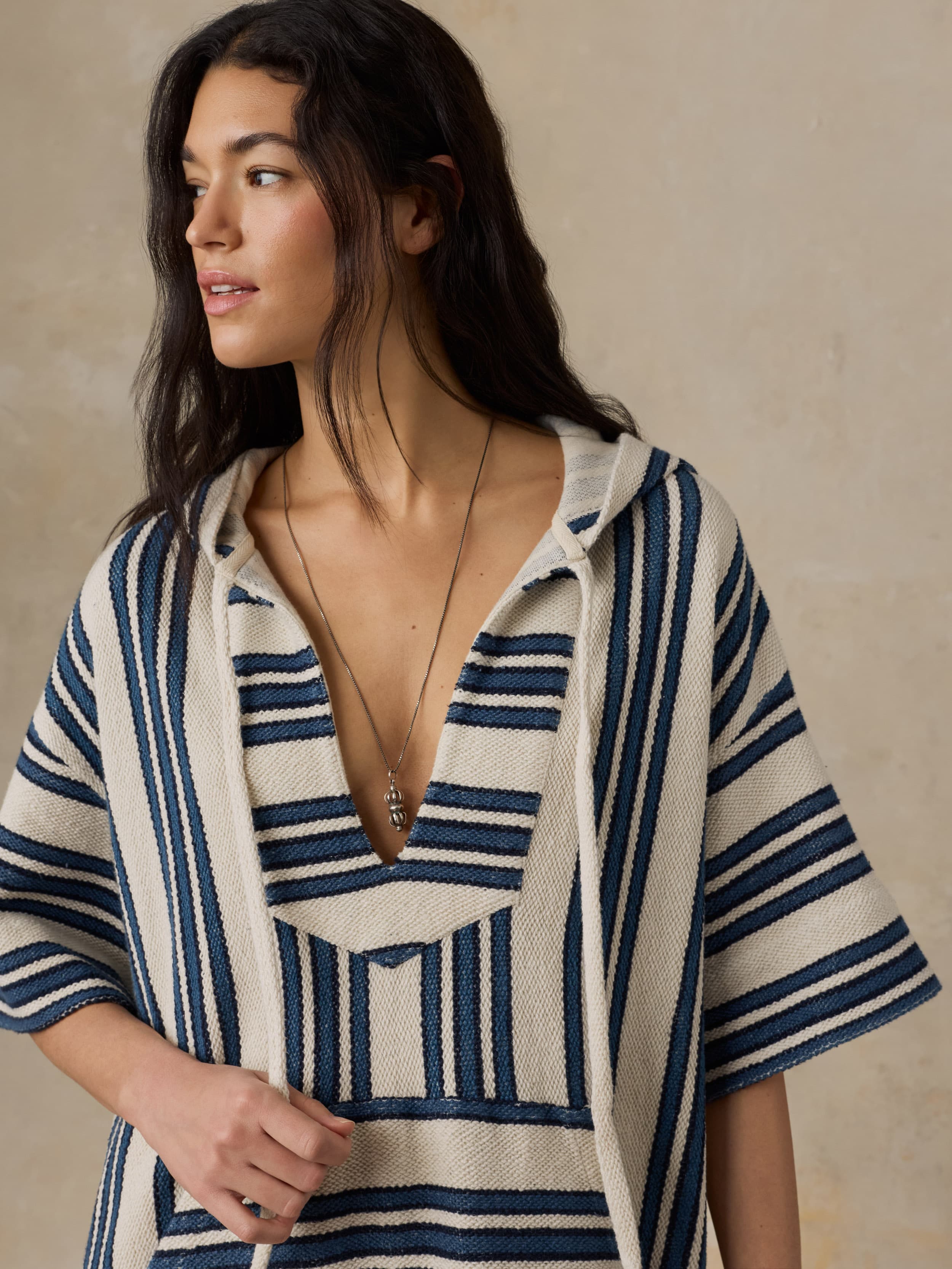 Woman wearing a blue and white striped dress against a beige background