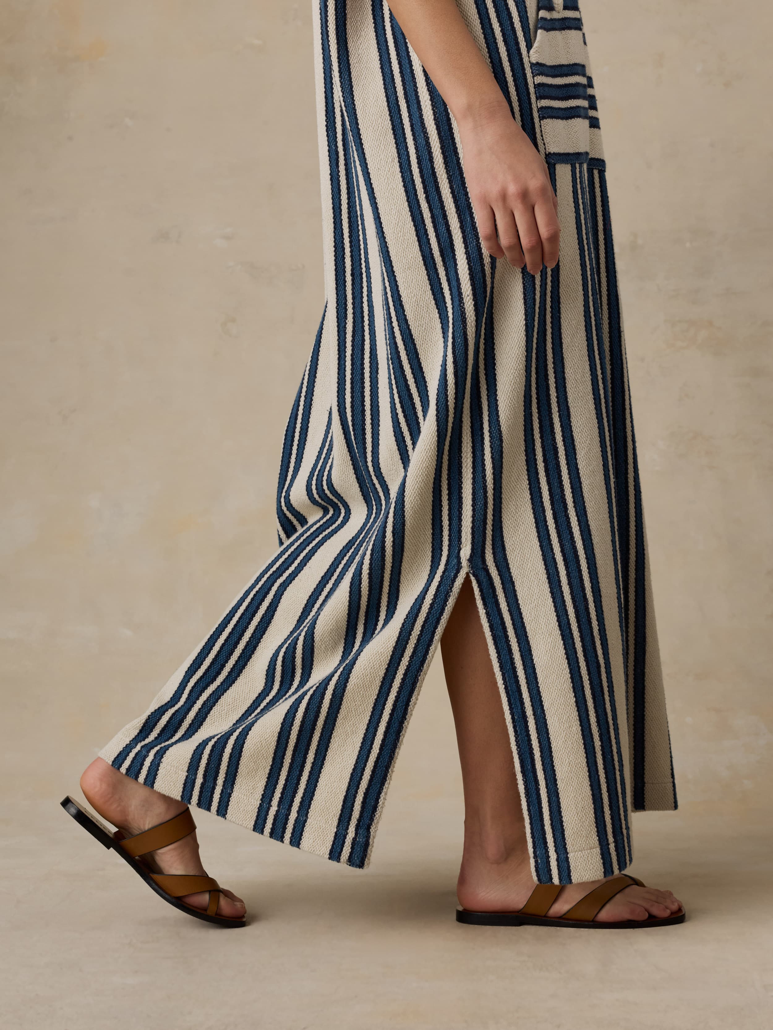 Woman wearing a long, striped dress with a neutral background