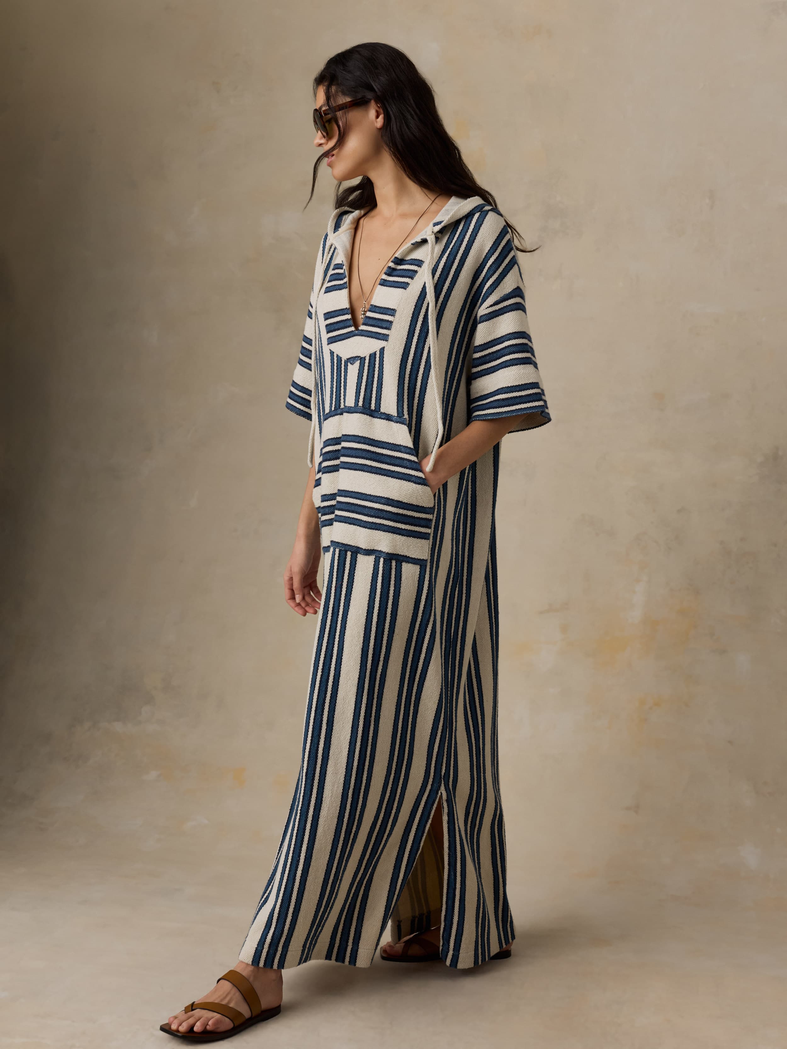 Woman wearing a blue and white striped dress against a beige background