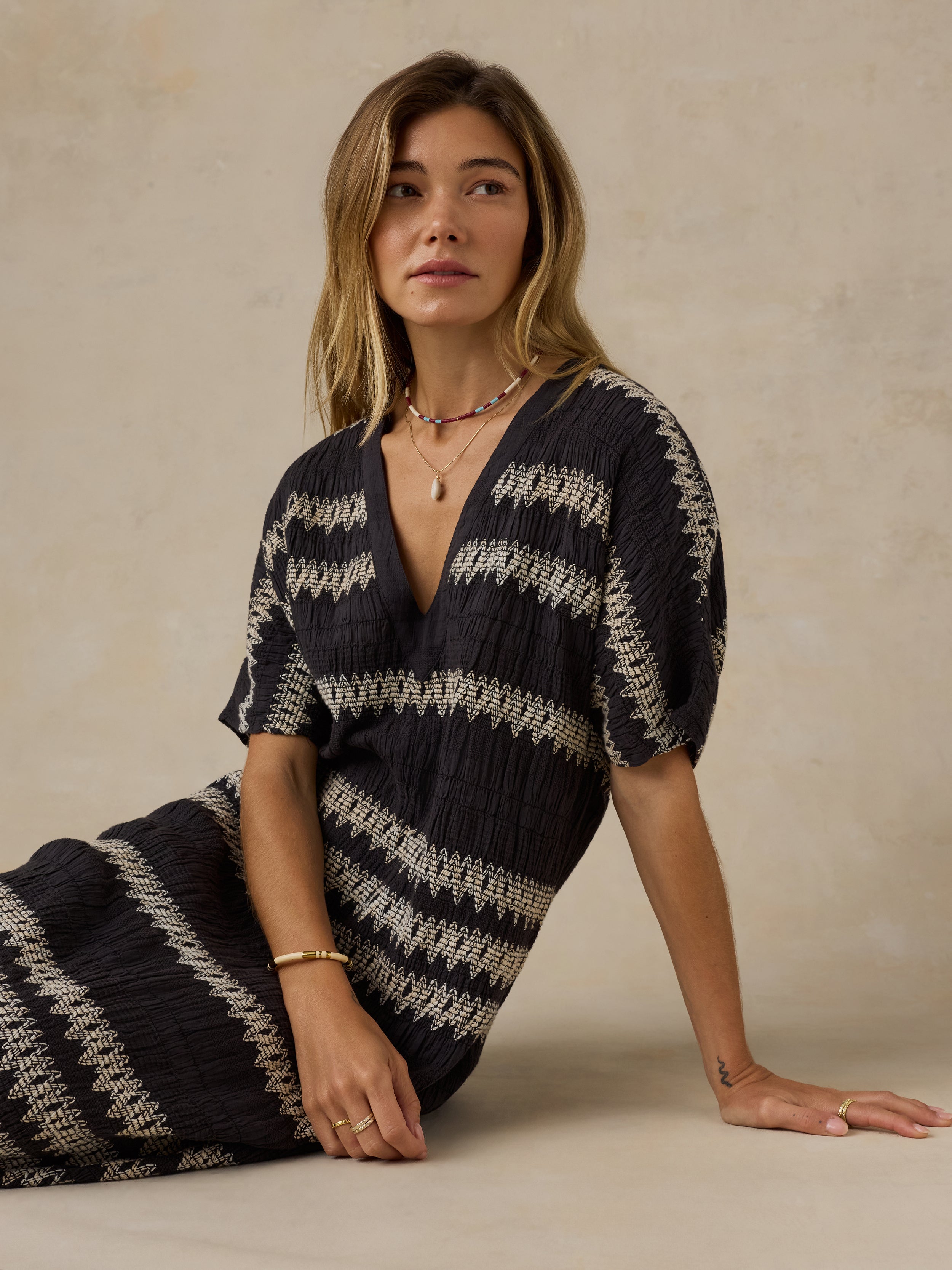 Woman wearing a black and white striped dress against a beige background