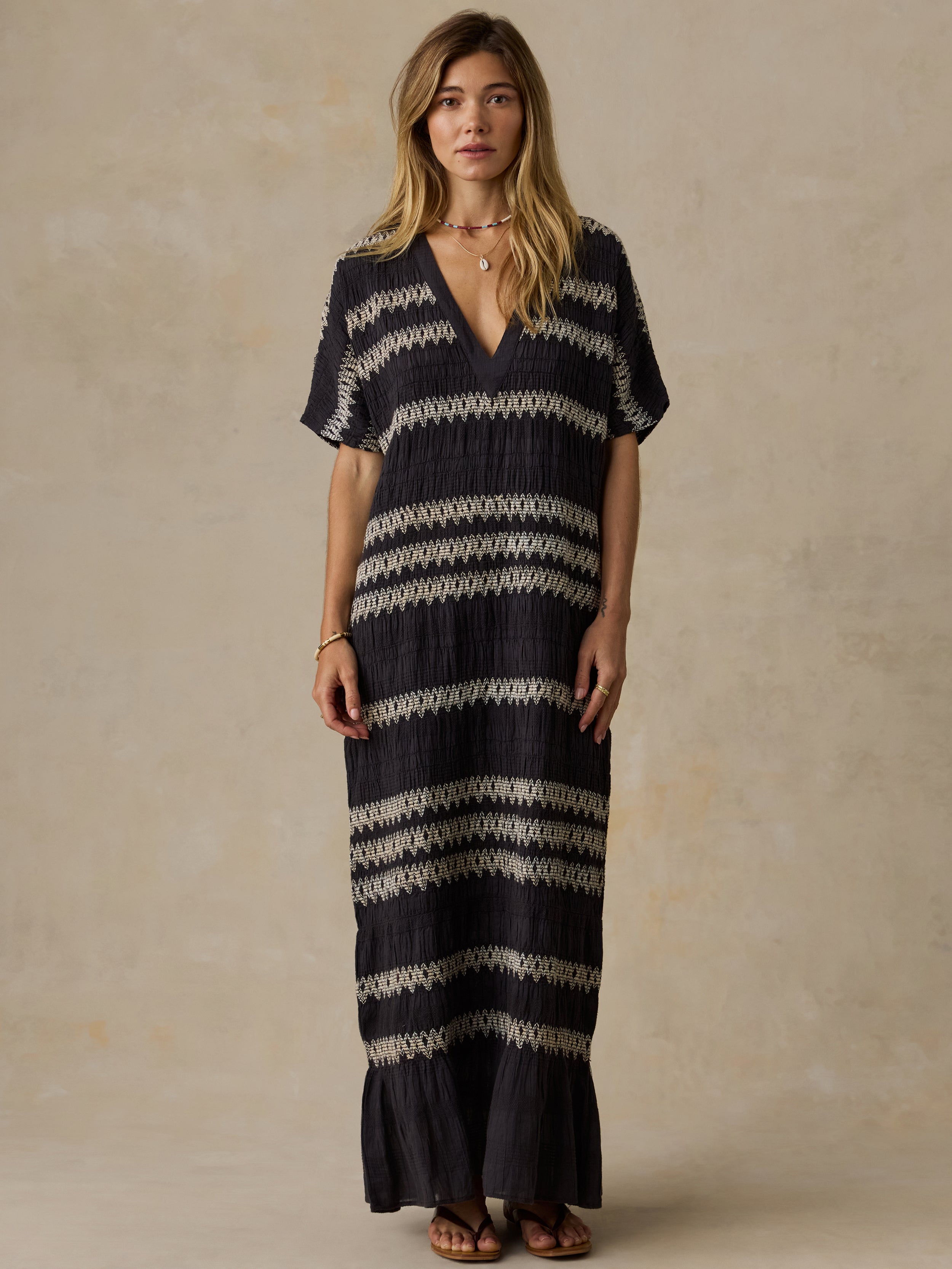 Woman wearing a black and white striped dress against a beige background