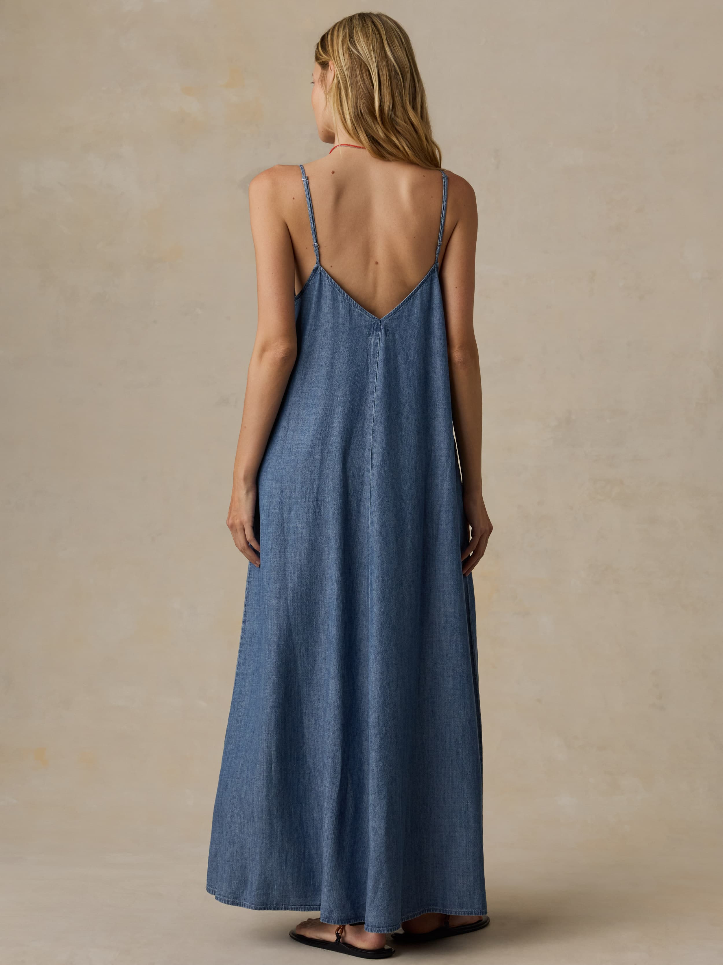 Woman wearing a blue maxi dress against a beige background