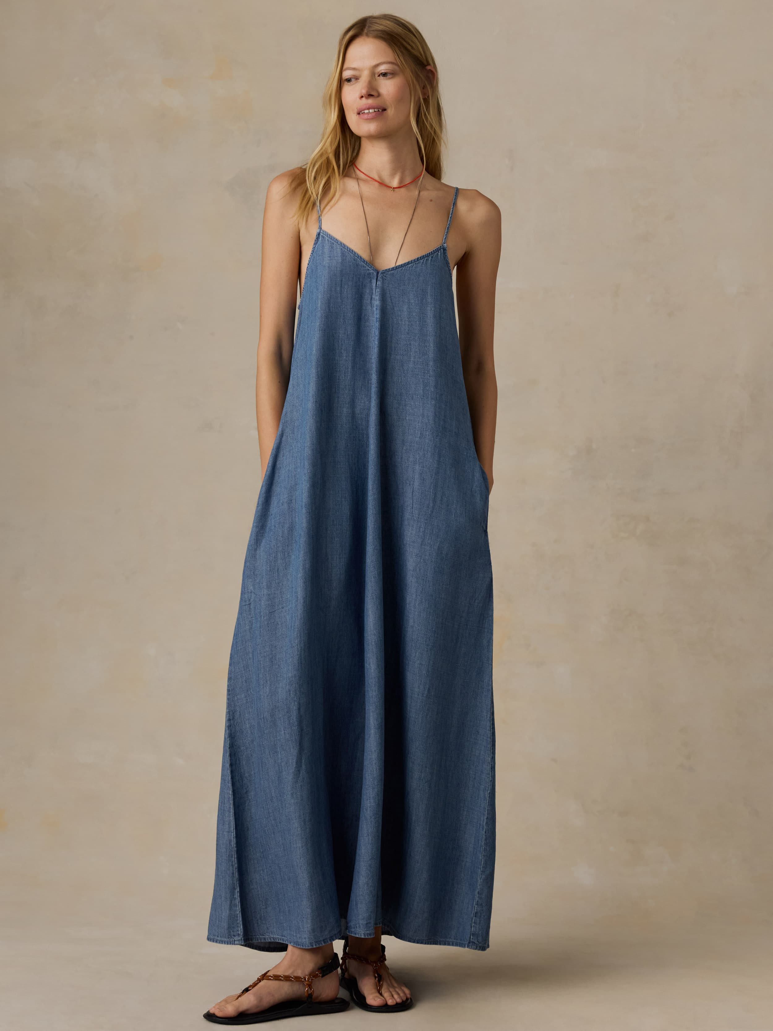 Woman wearing a blue maxi dress against a beige background