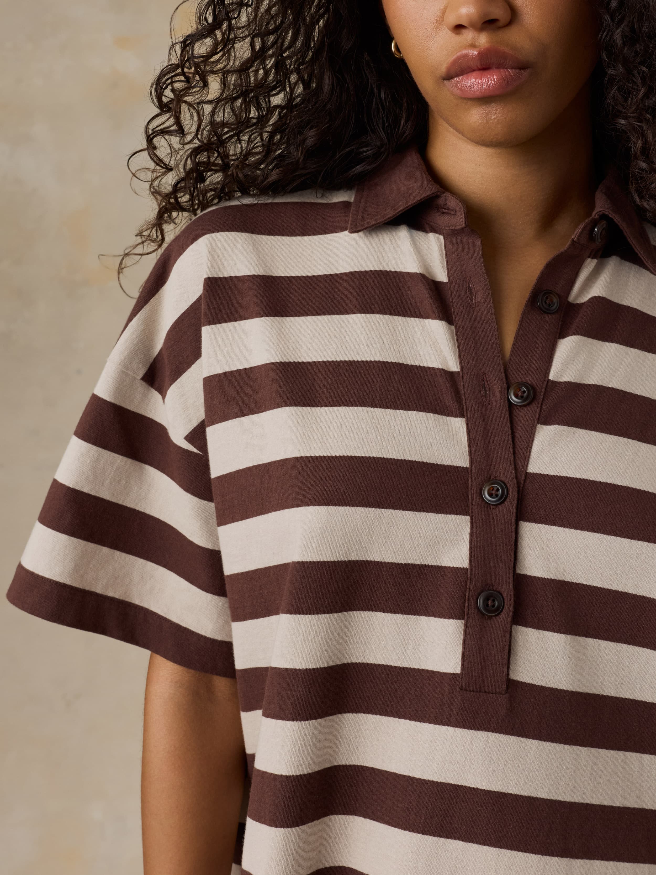 Woman wearing a brown and white striped dress against a beige background
