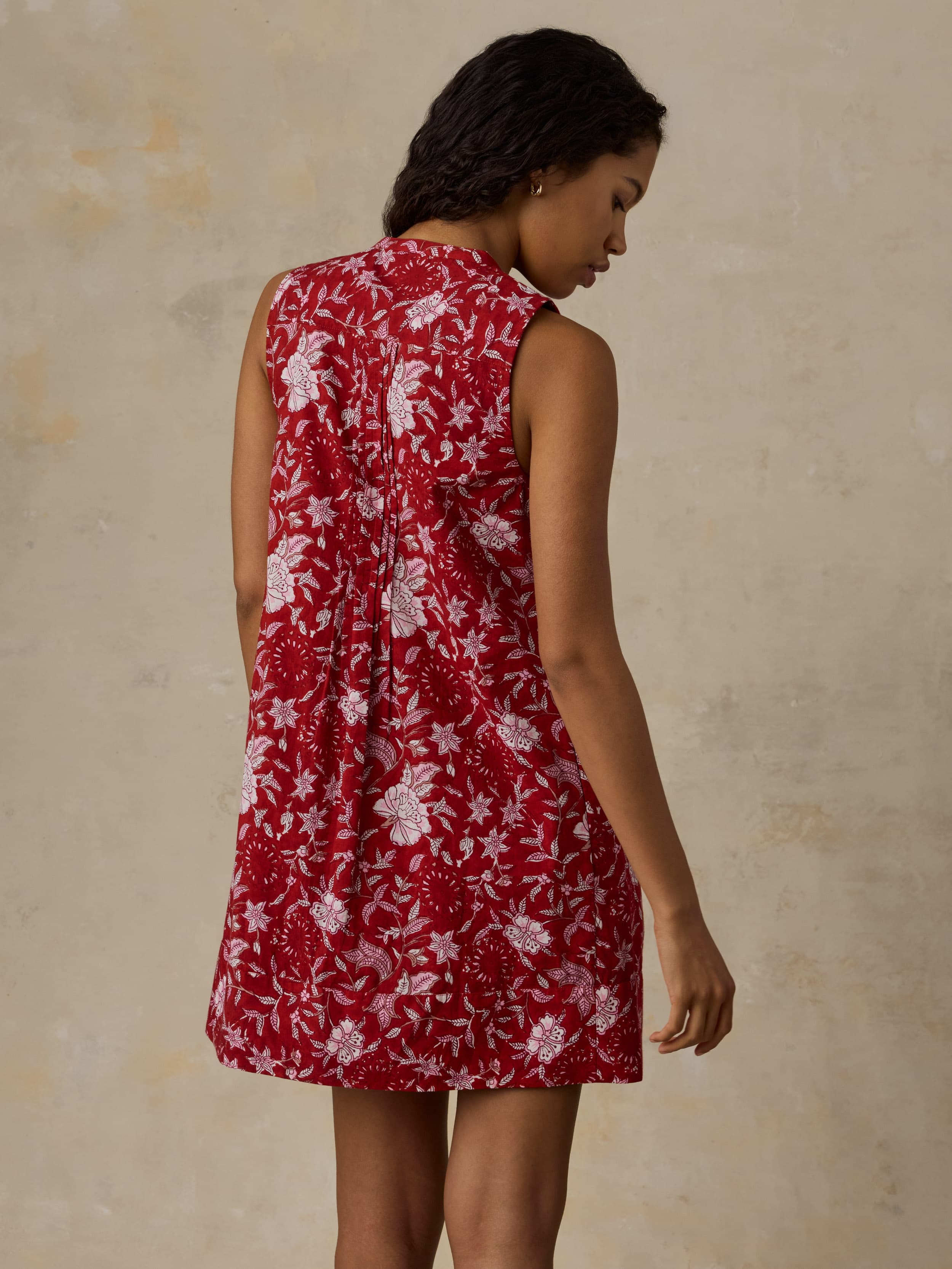 Woman wearing a red floral dress against a beige background