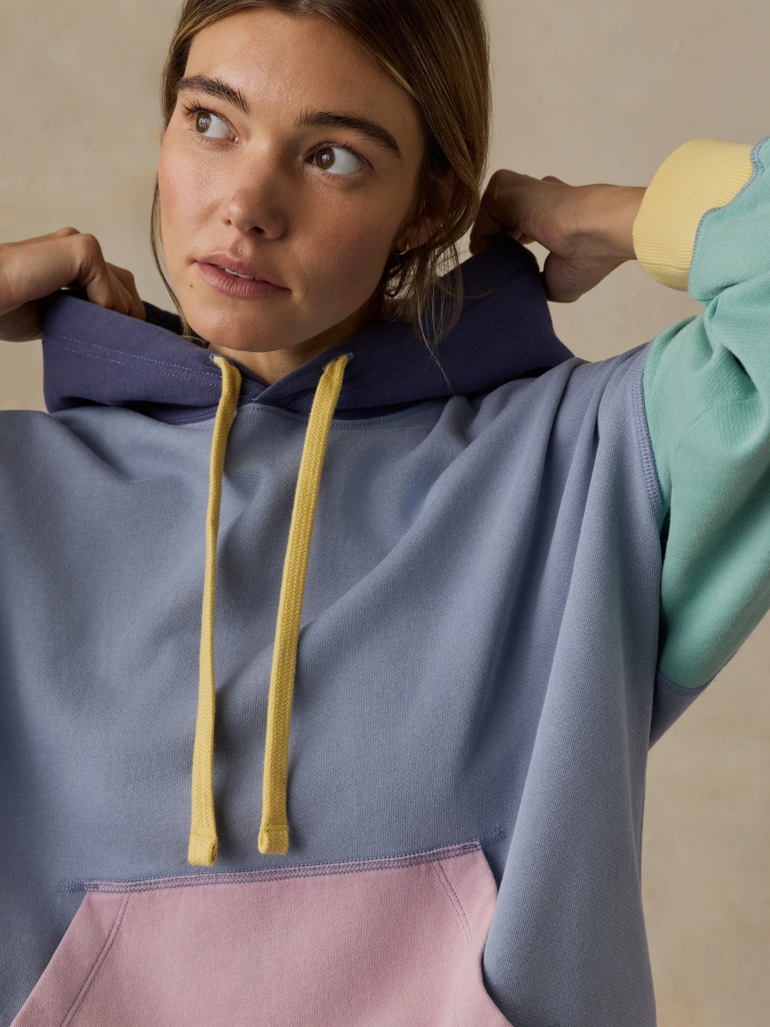 Woman wearing a colorful hoodie against a beige background