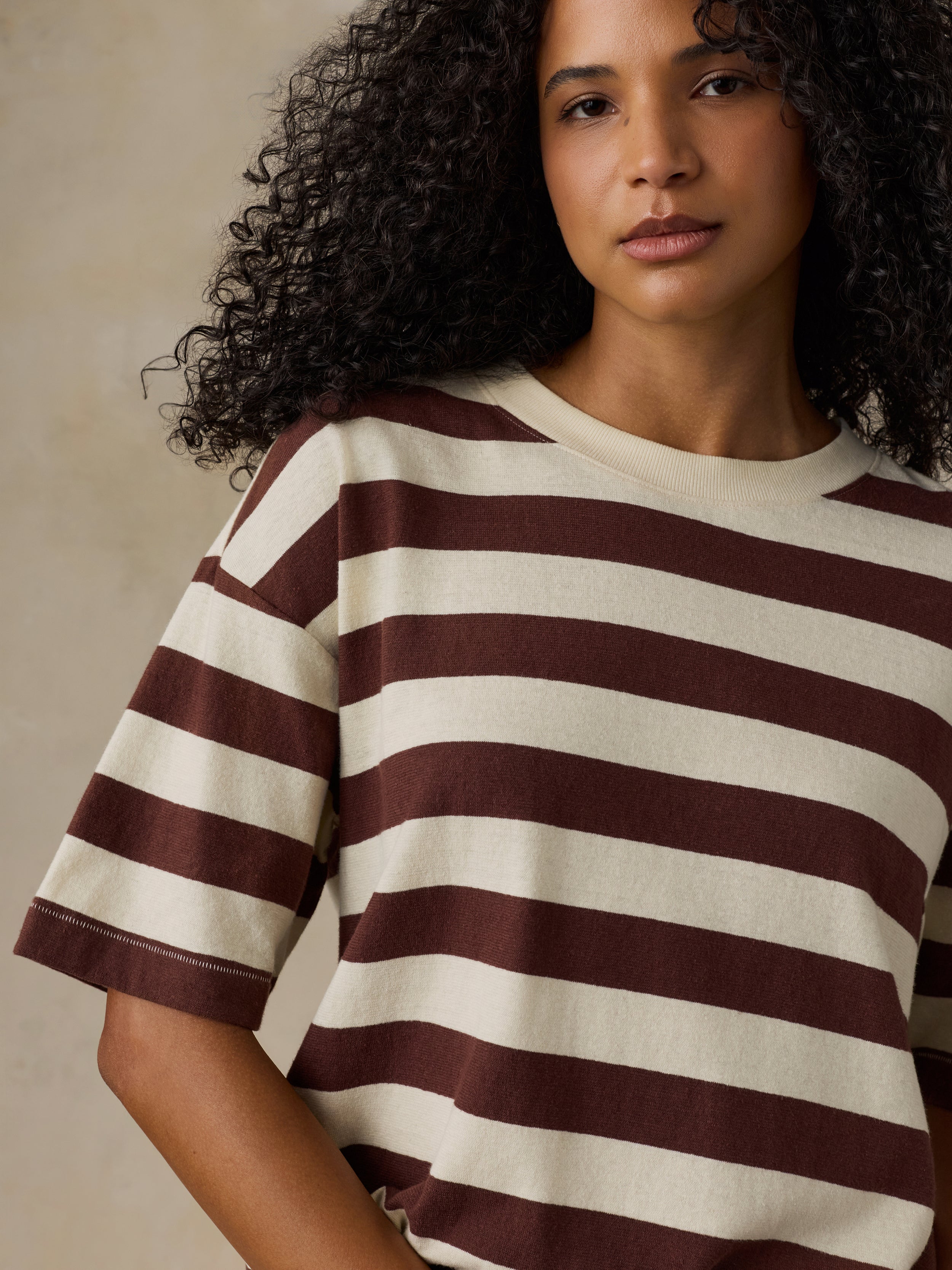 Woman wearing a brown and white striped shirt against a beige background