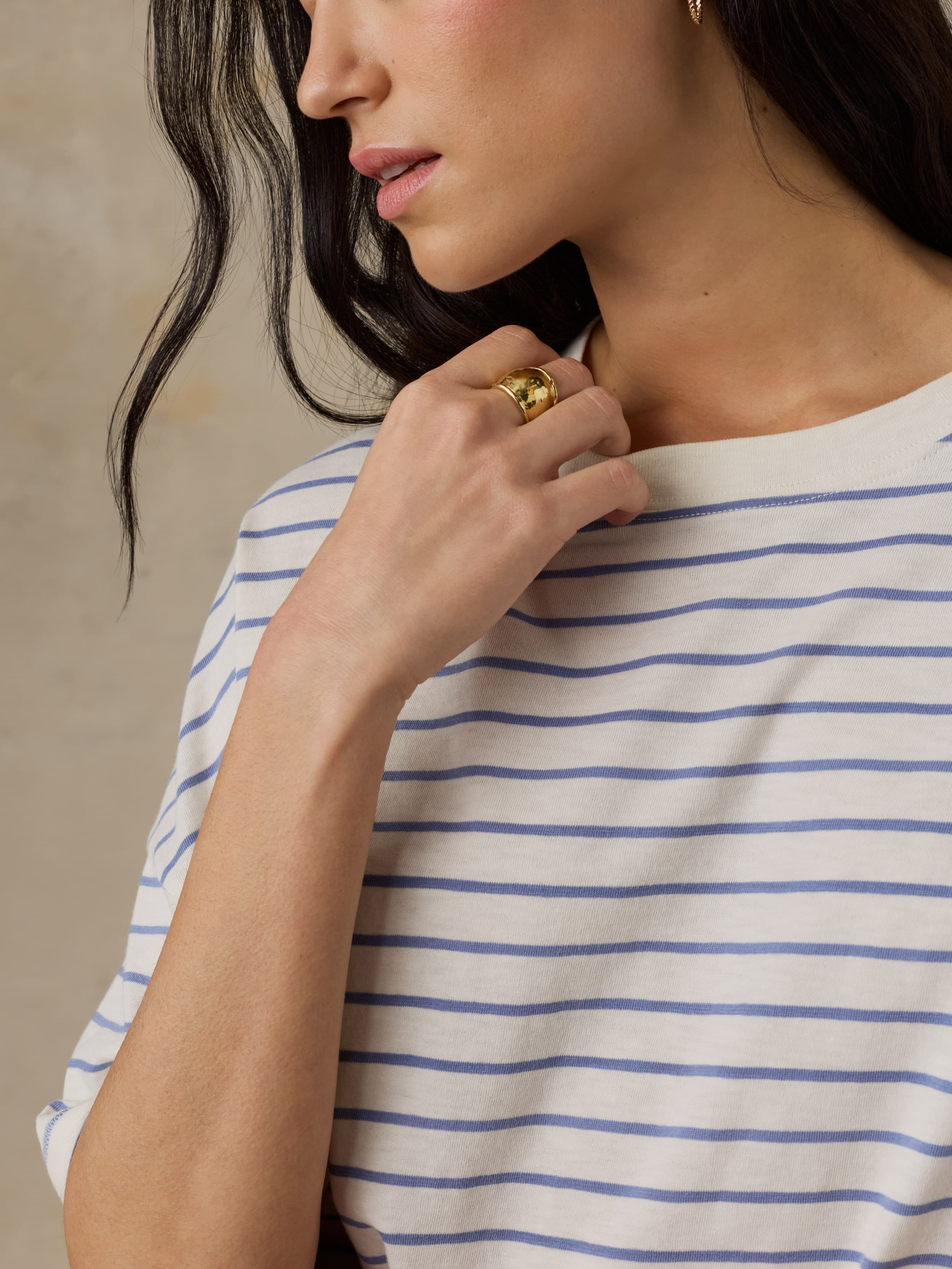 Woman wearing a white and blue striped shirt with a neutral background