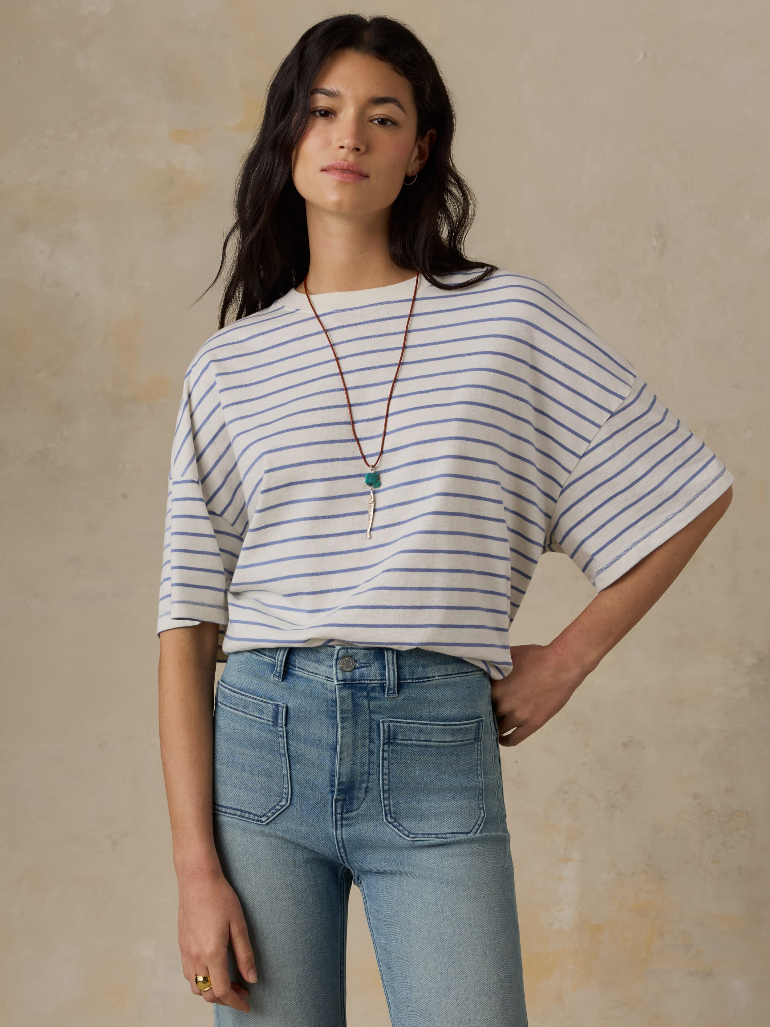 Woman wearing a striped shirt and jeans against a beige background