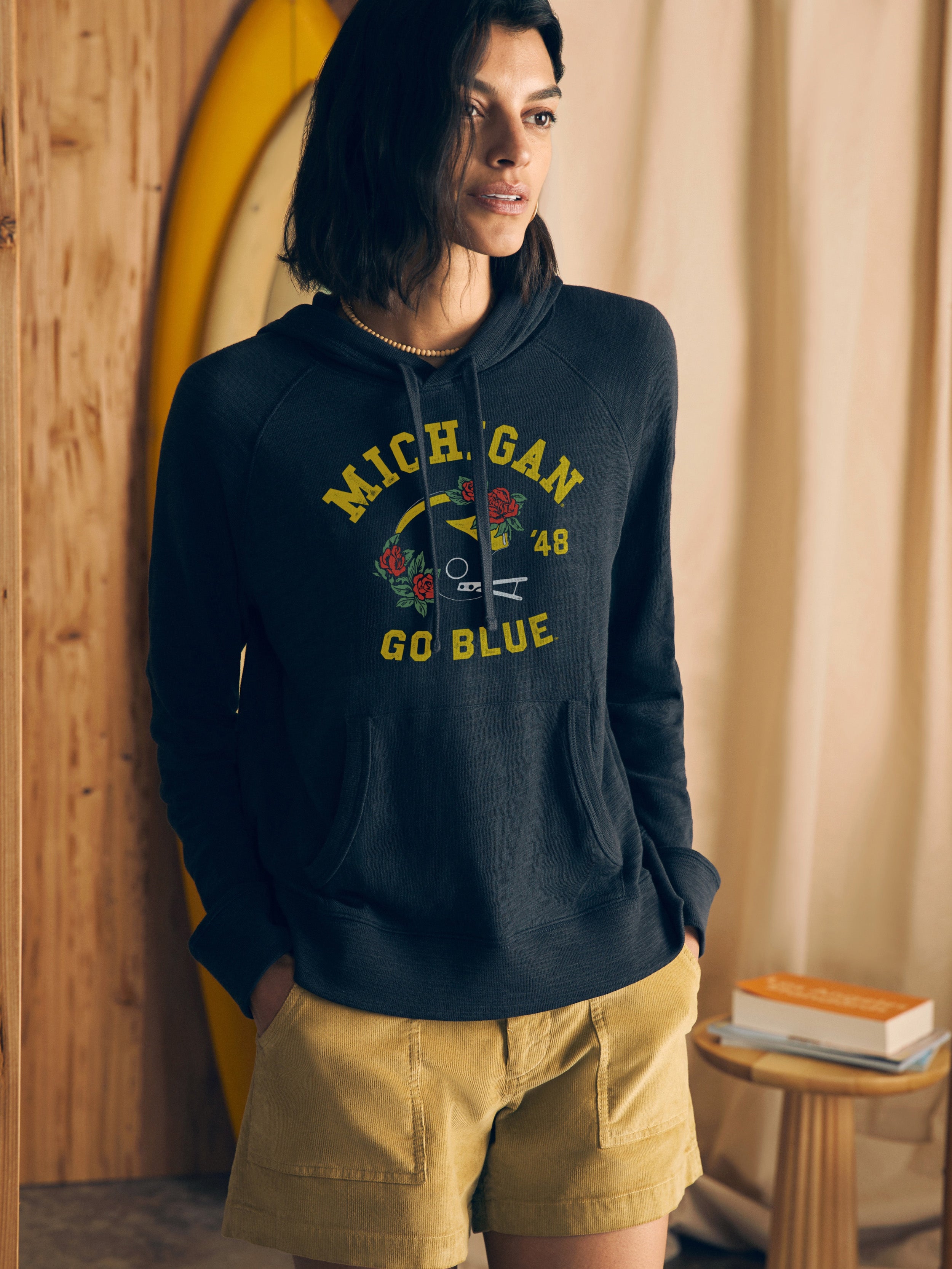 Woman wearing a navy hoodie with University of Michigan graphic at the center chest