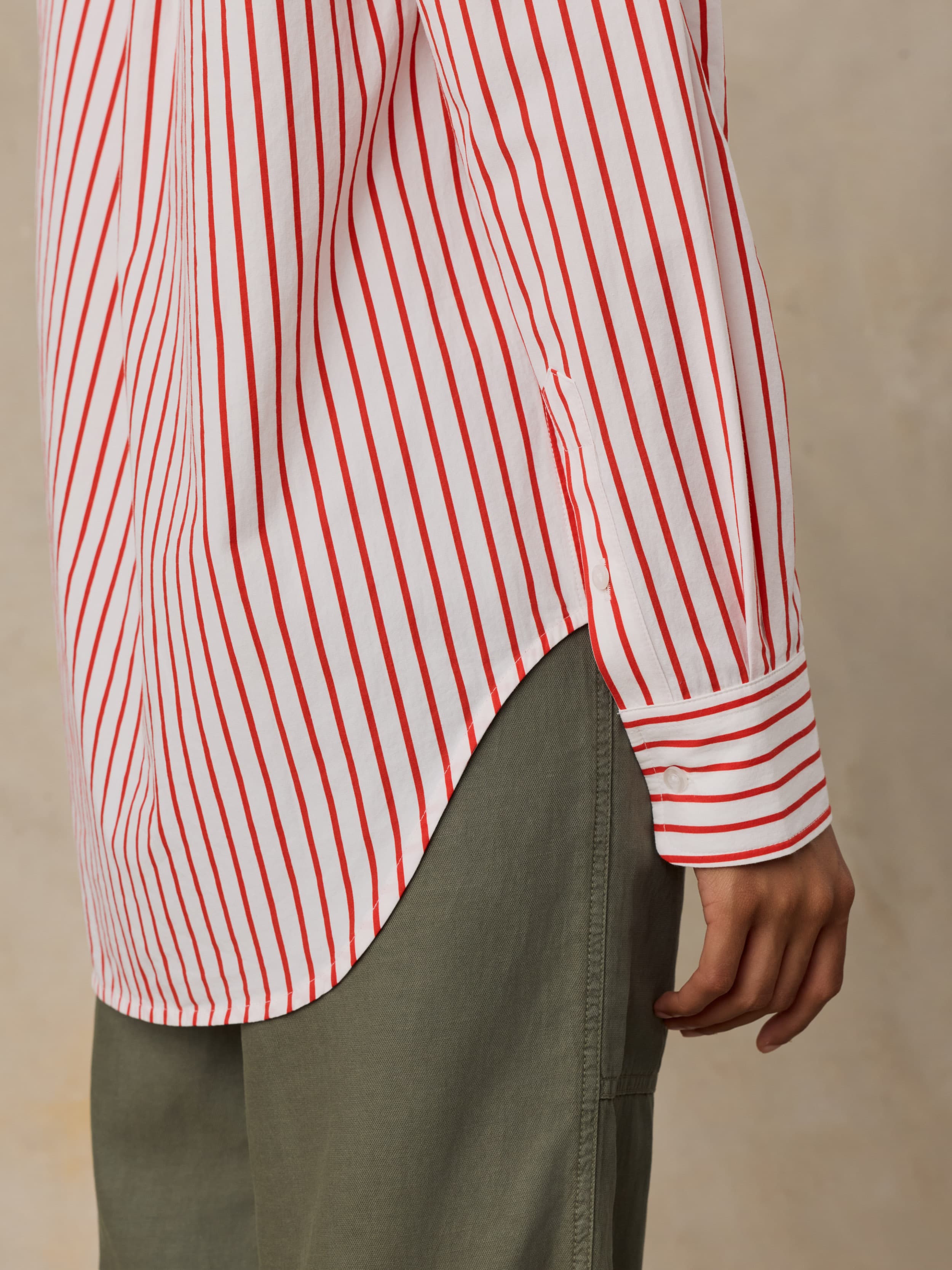 Woman wearing a red and white striped shirt with green pants on a neutral background