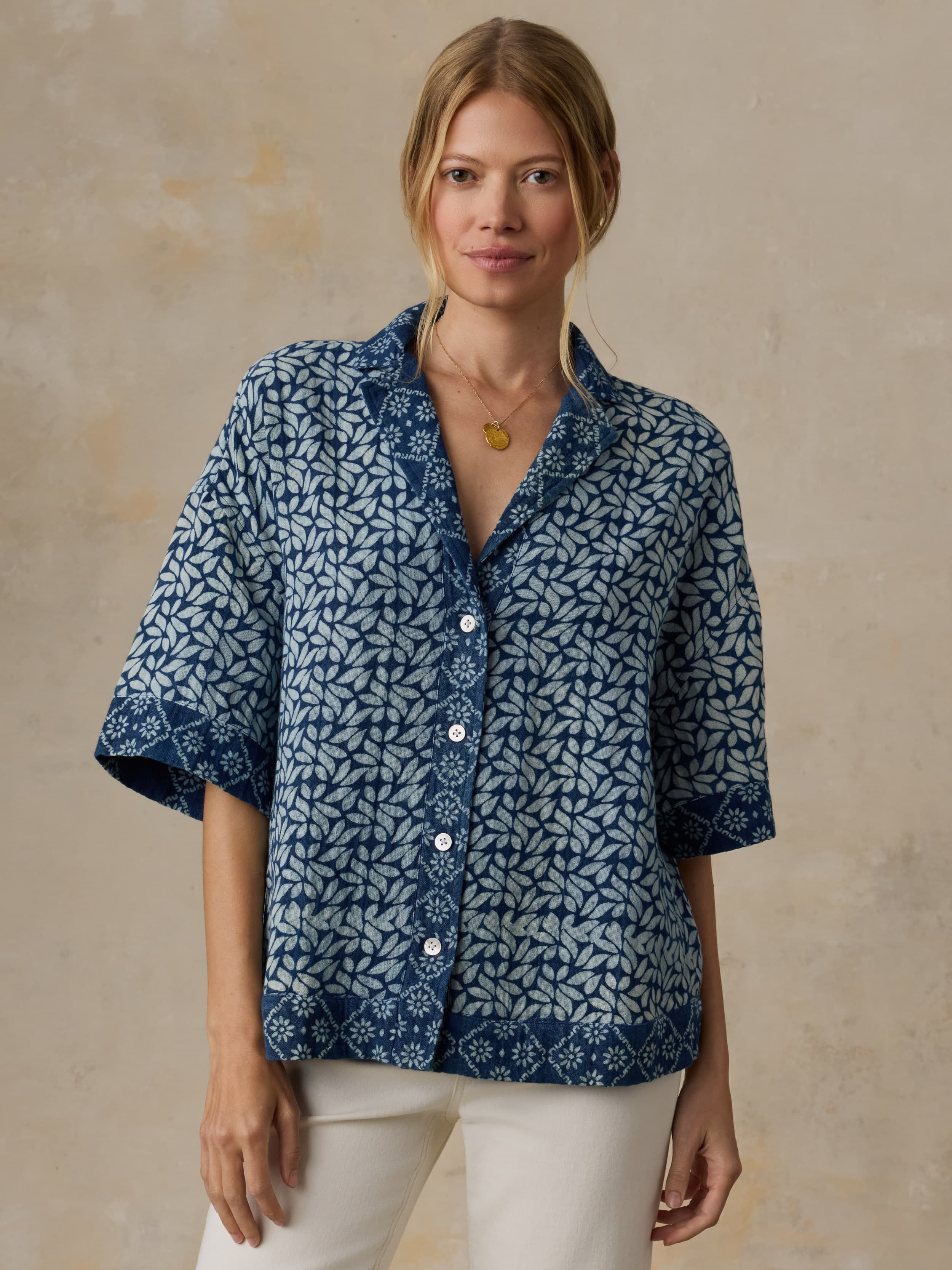 Woman wearing a blue patterned shirt against a beige background